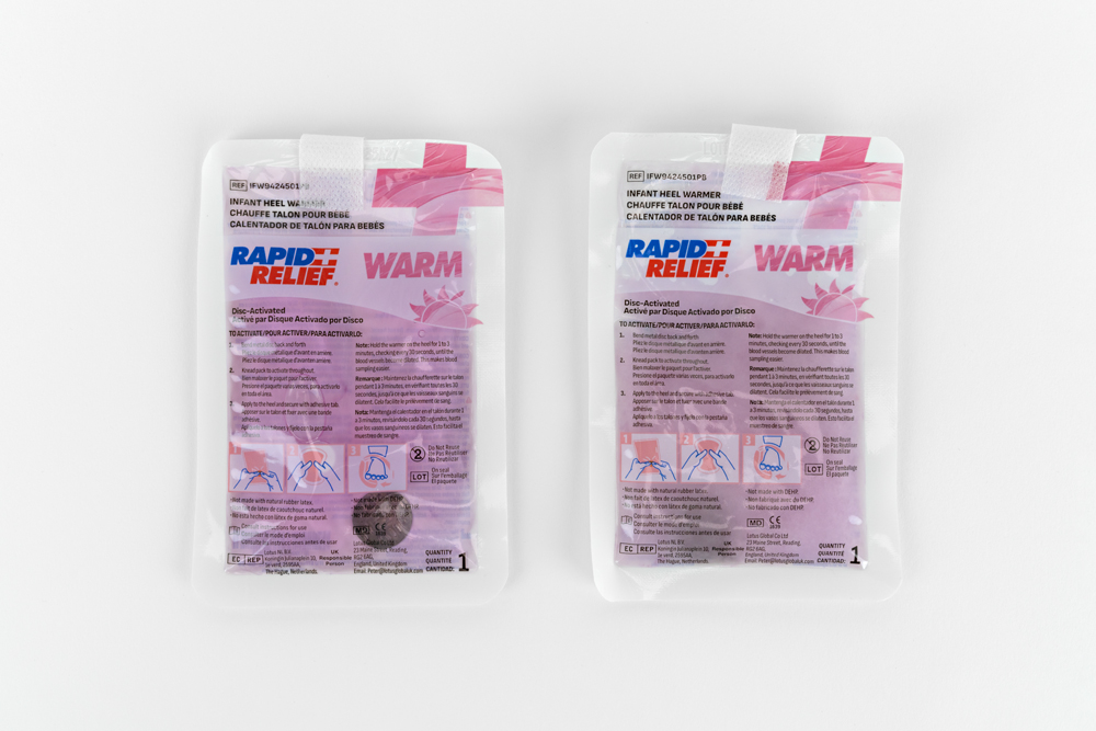 Two Typenex Medical clear infant heel warmer packages displayed flat, showing front and back views.