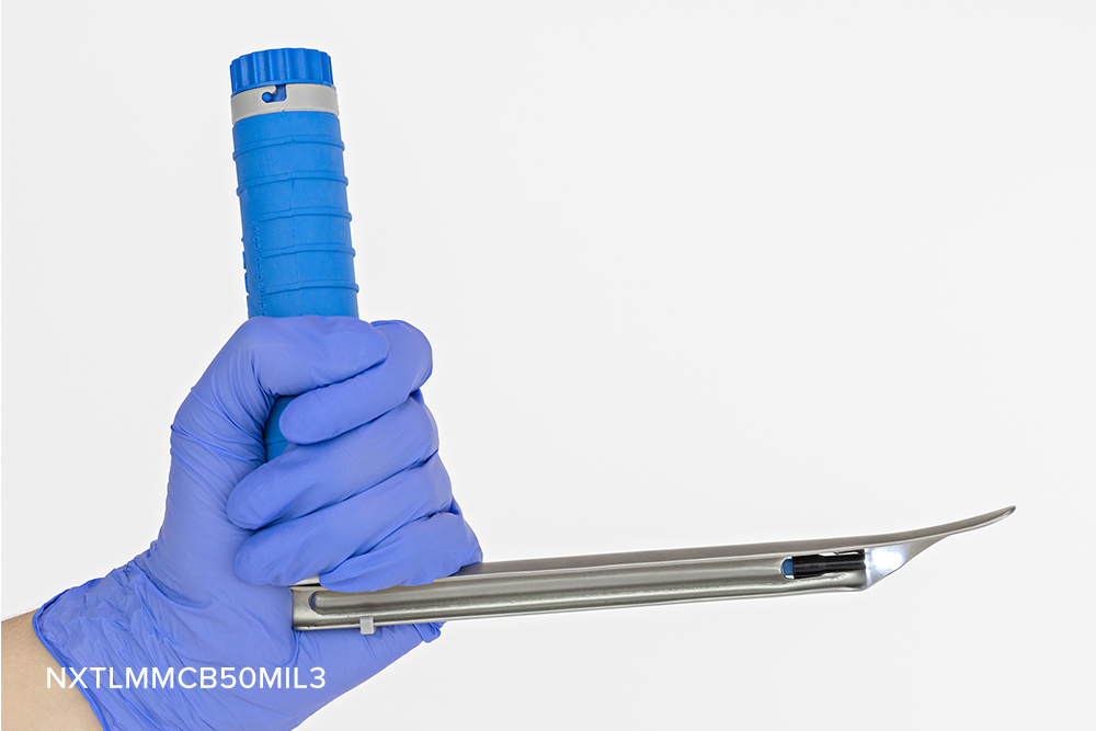 Gloved hand holding disposable laryngoscope blade and handle set, with illuminated blade.