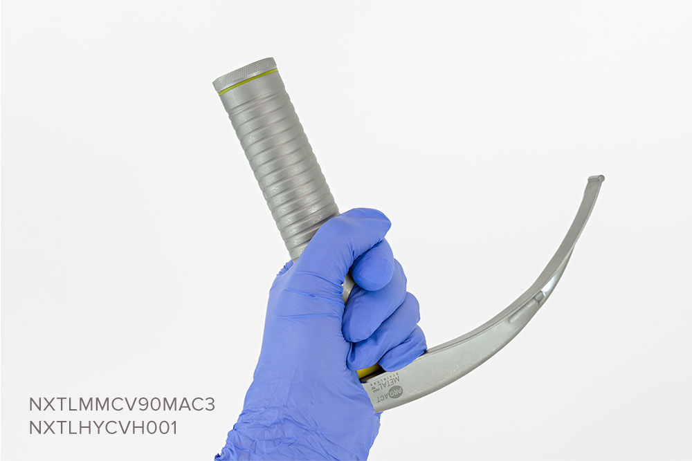 Gloved hand holding reusable handle, with disposable Macintosh laryngoscope blade and integrated LED light source.