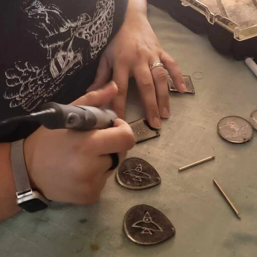 The artist, carving into resin jewelry with a dremel tool.
