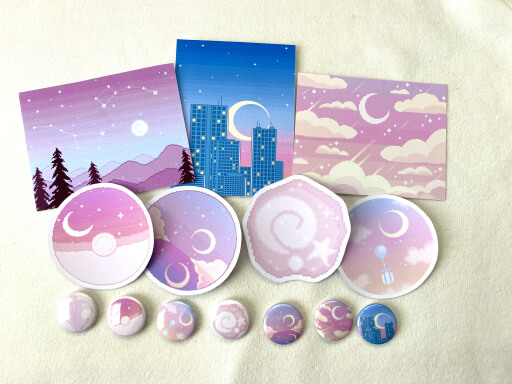A picture of three art prints, four stickers, and seven pinback buttons of dreamy celestial pixel art.