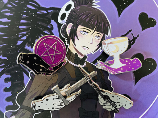 Four enamel pins arranged on top of an anime portrait print. The pins are of the tarot aces: a hand holding a pentacle, a hand holding a cup, a hand holding a wand, and a hand holding a sword. All are done in the colors of the asexual pride flag: black, grey, purple, and white. The portrait print is of a goth girl with black hair, bangs, pale eyes and skin. She smiles against a purple background, where hearts and the partial image of a black skeleton surround her.