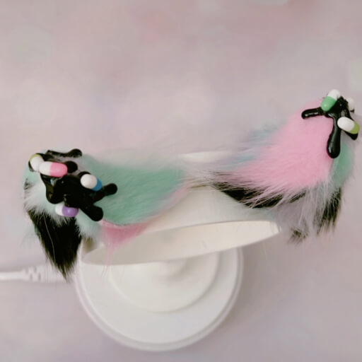 A pair of yamikawaii themed costume ears on a headband. There is a black drippy sauce on the tips, and decorative pills are on top of them.