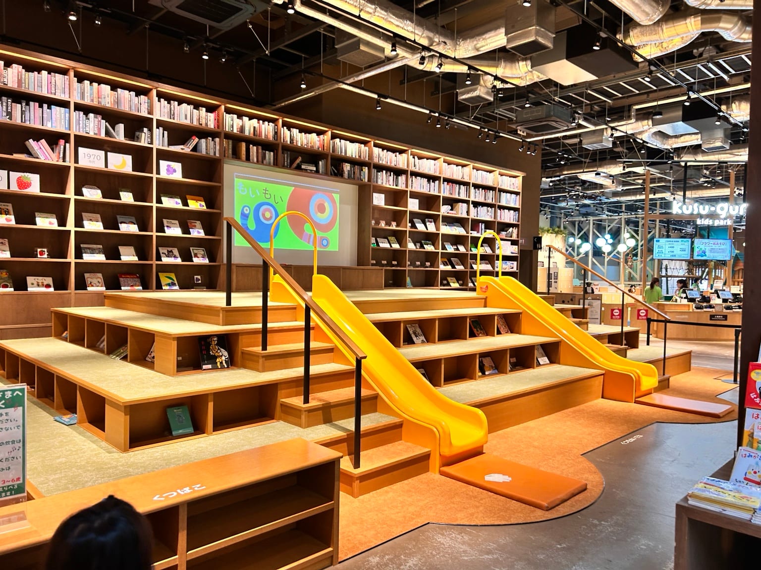 絵本棚と黄色いすべり台があるTSUTAYA BOOKSTOREのキッズ向けスペース