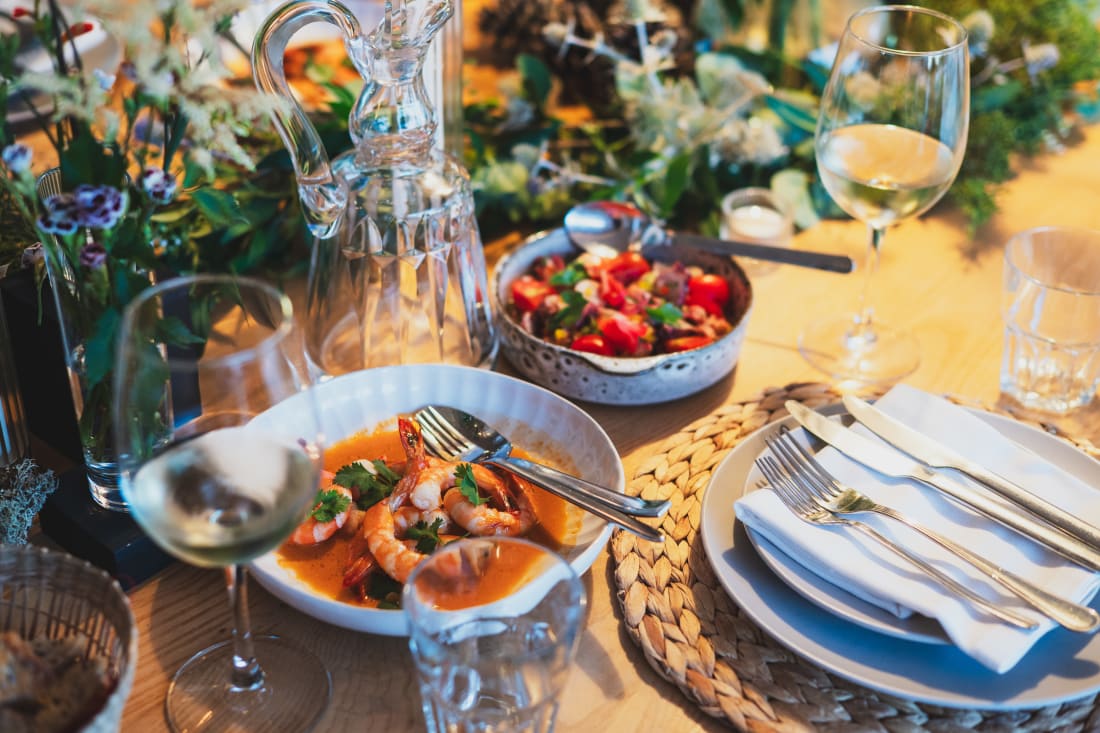 Summer tablescape in Comporta, Portugal with woven place settings, loose foliage, tall flowers and candlelight.