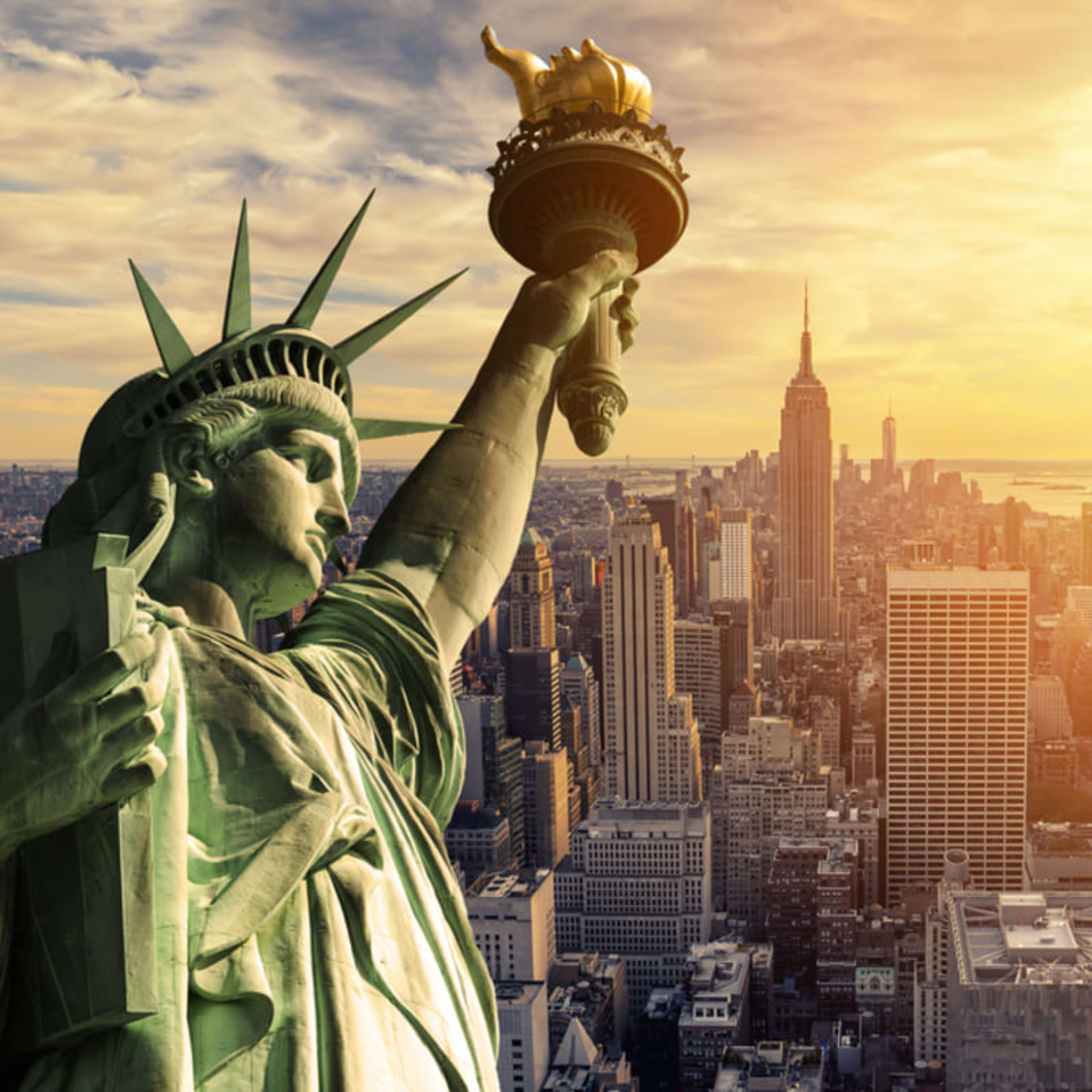 Statue of Liberty in close-up with the New York skyline beyond.