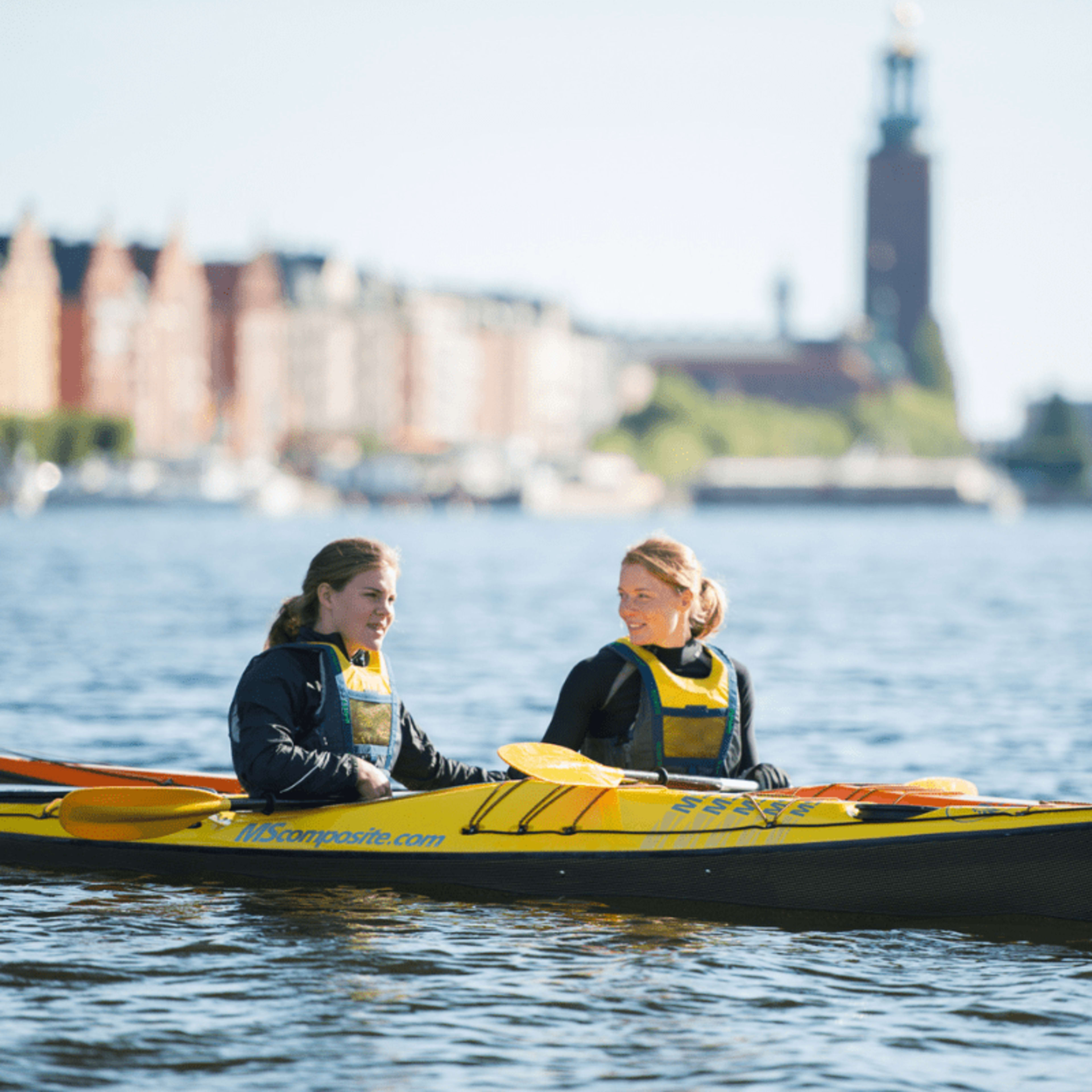 Kayakers in Stockholm with City Hall silhouetted in the background.