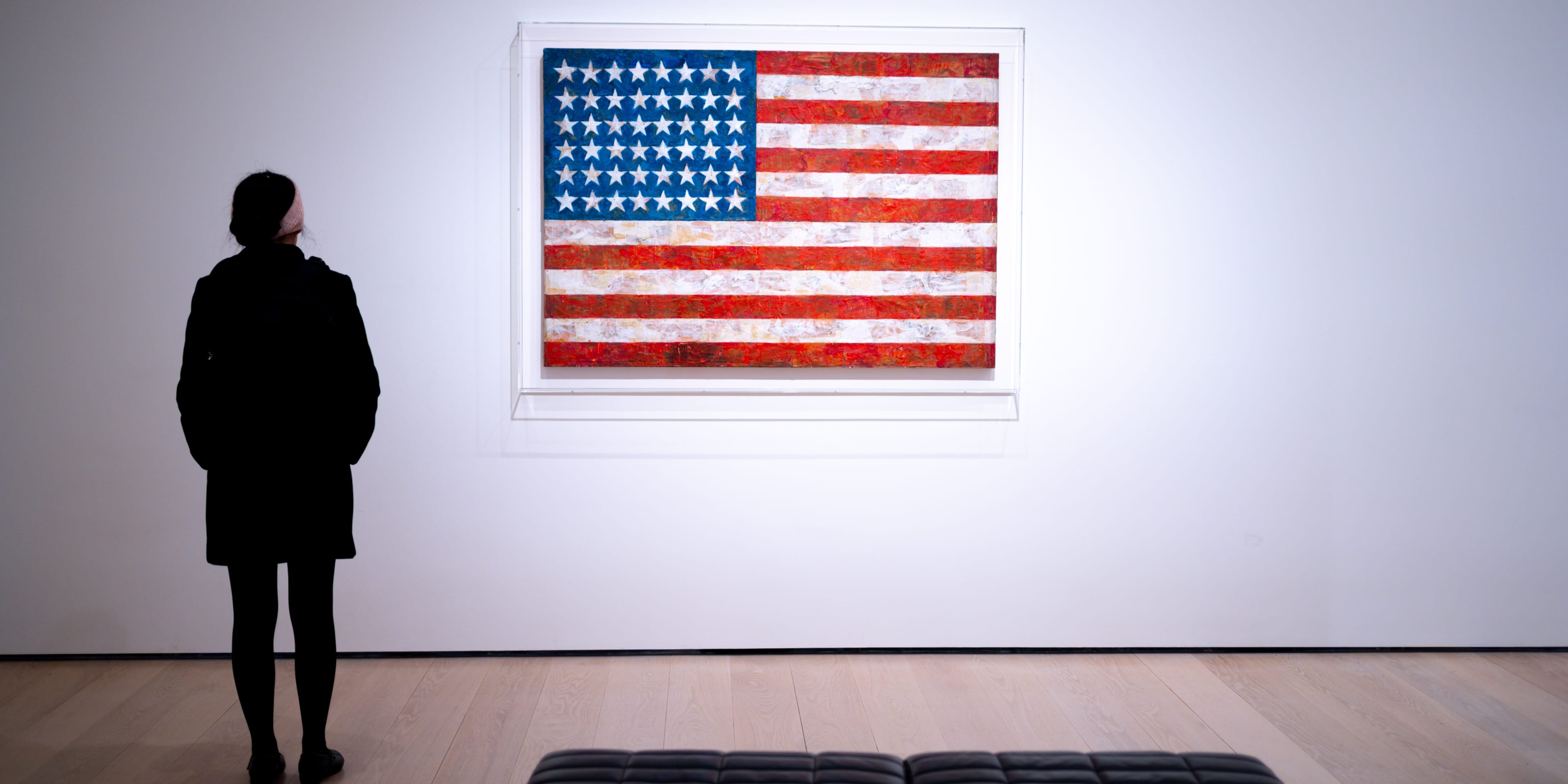 Una persona contempla una obra con la bandera de Estados Unidos en un museo. 