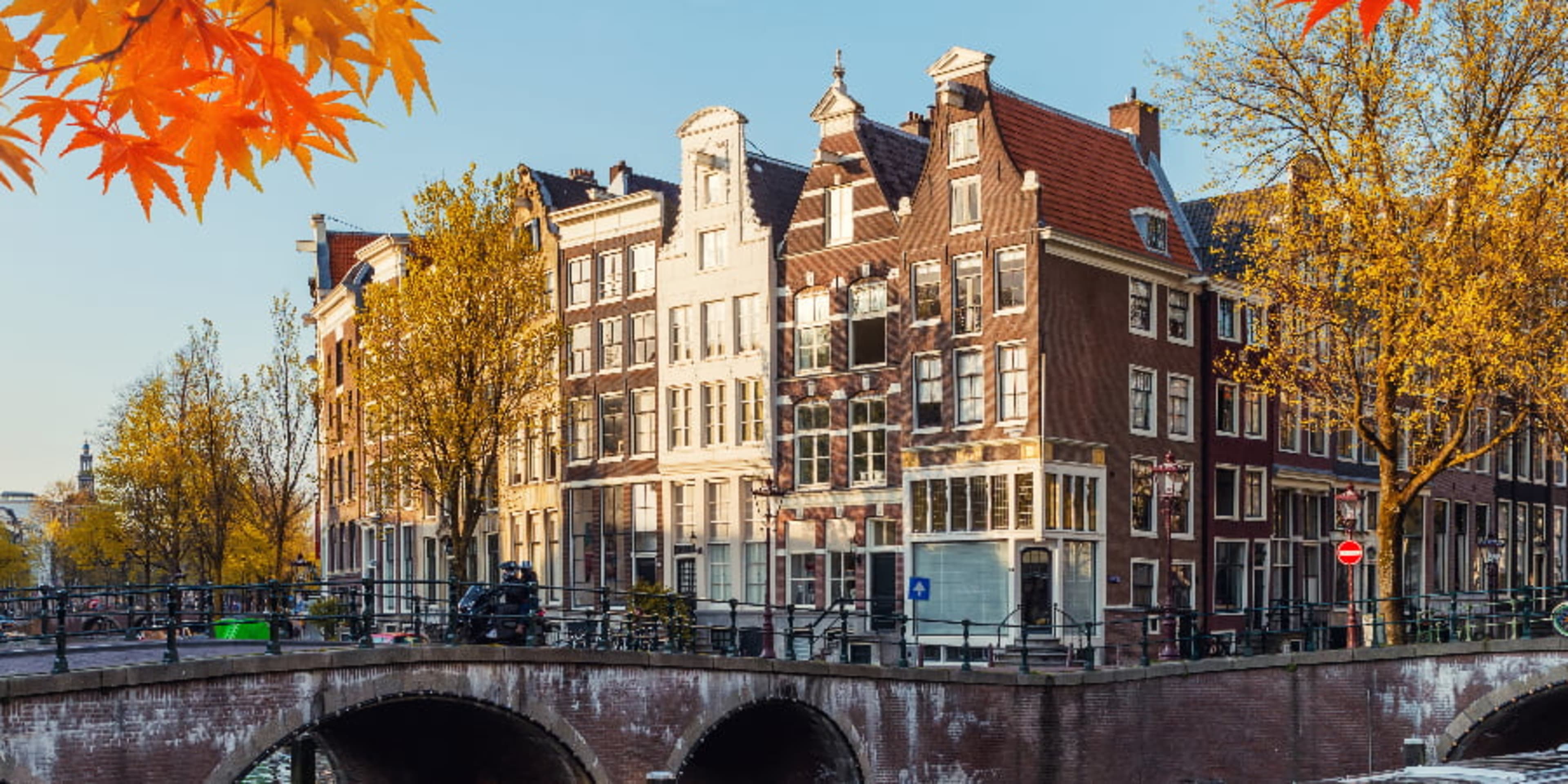 Amsterdam bridge and canal houses surrounded by fall-colored trees