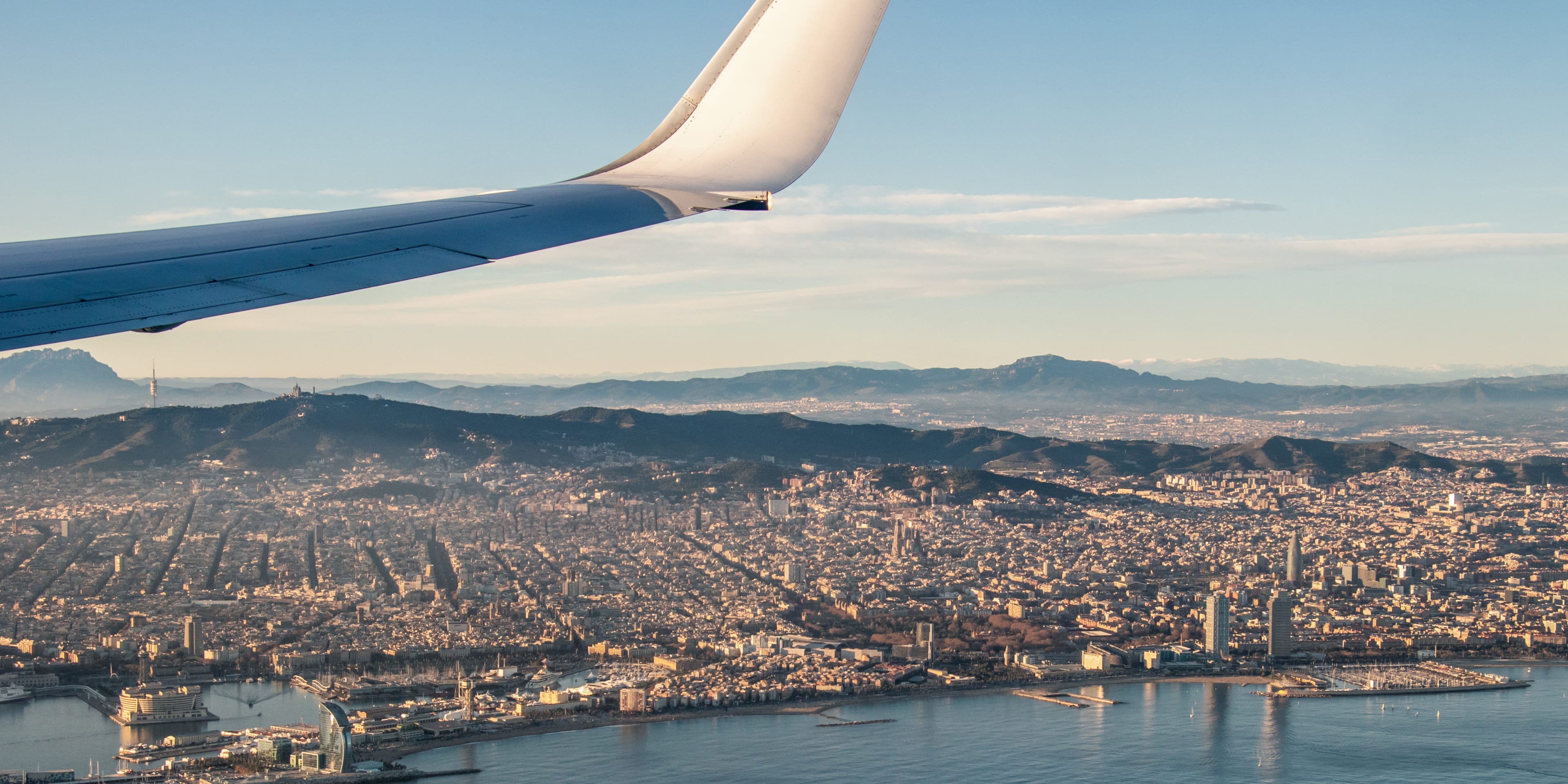 Vue de la ligne d'horizon de Barcelone depuis le hublot d'un avion. Le mont Tibidabo en arrière-plan. Coucher de soleil.