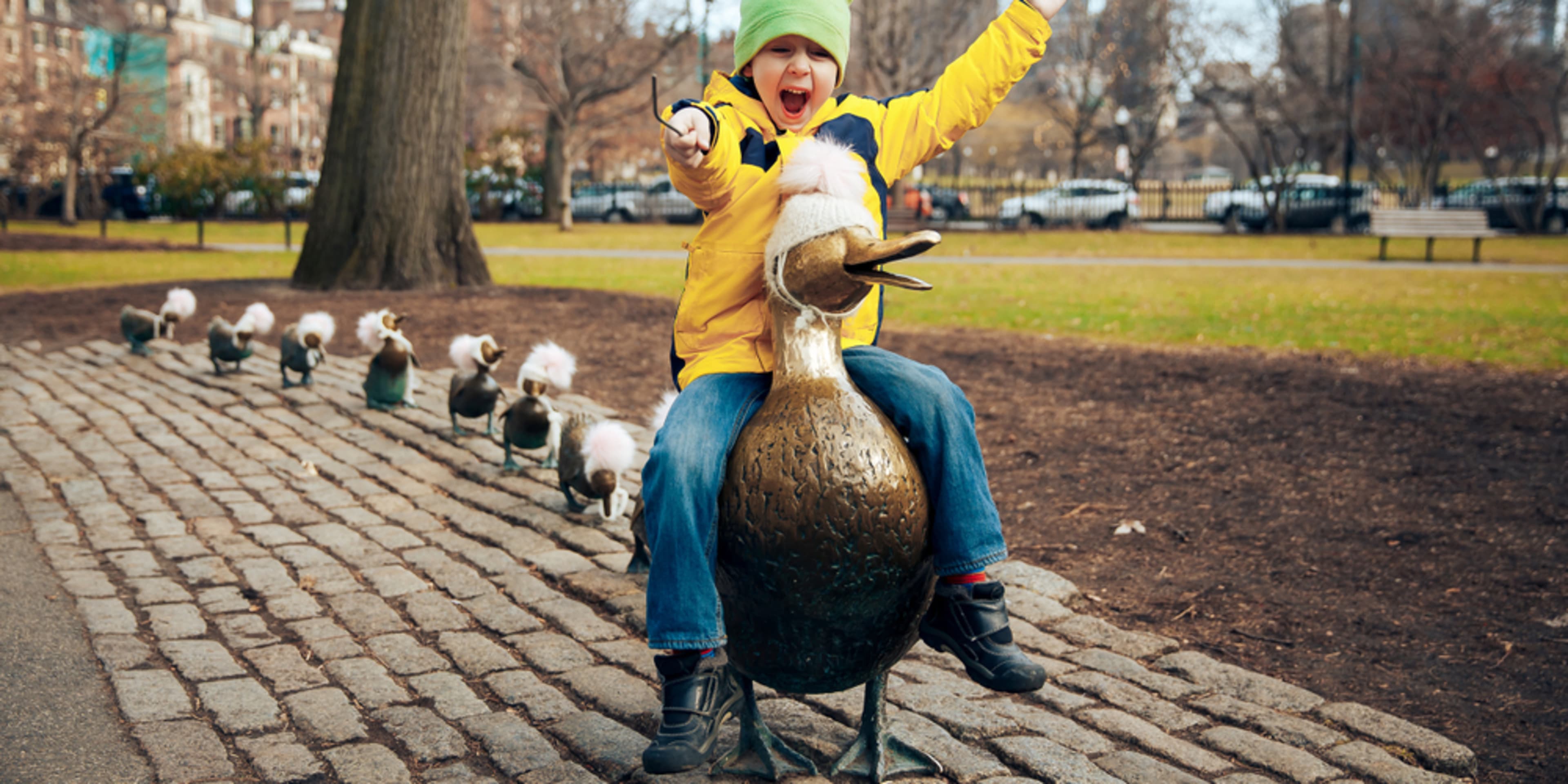 Niño subido a una estatua de patitos en un parque de Boston. Planes familiares en Boston.