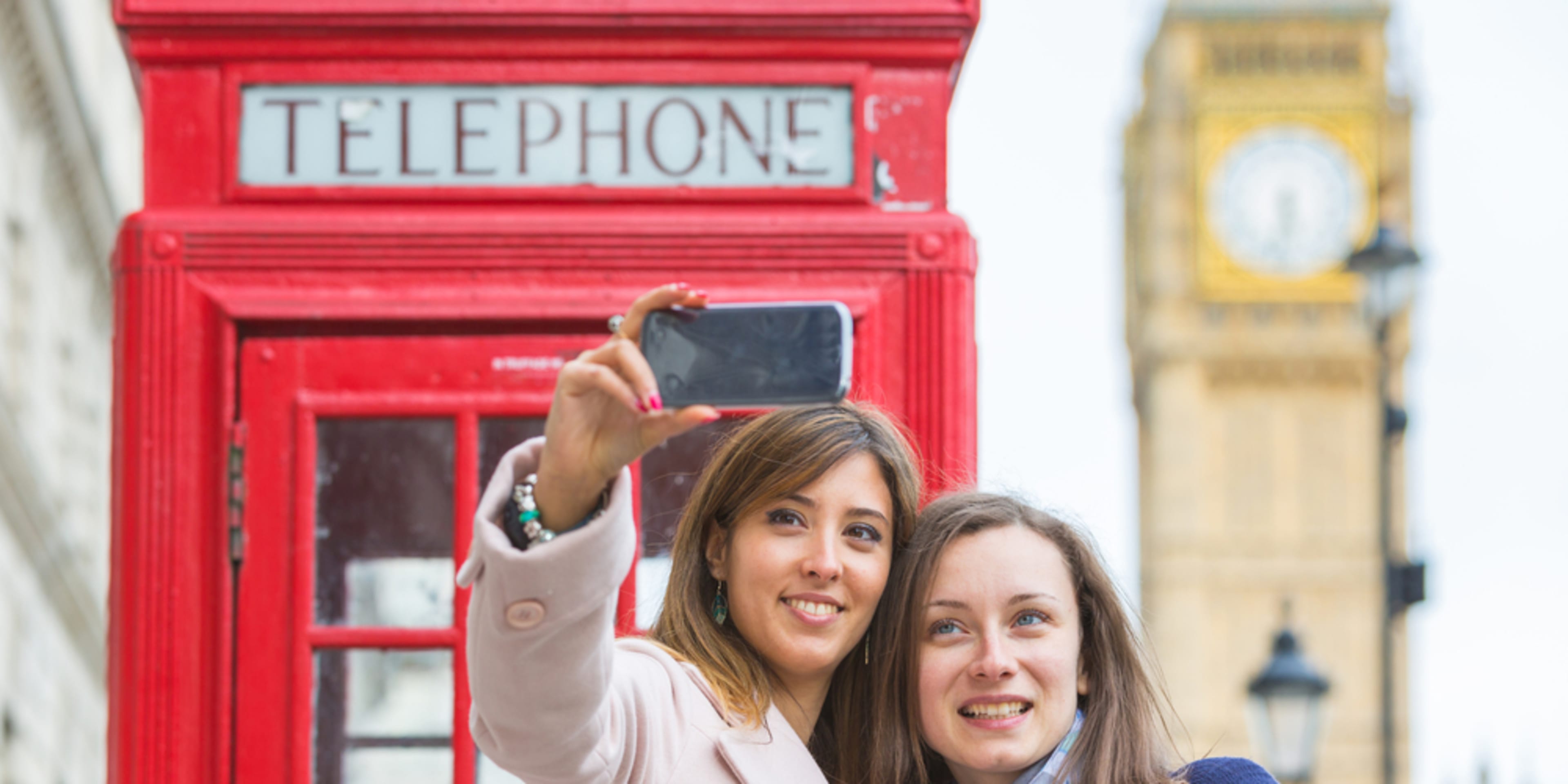 Turistas tirando selfies em frente ao Big Ben e a uma cabine telefônica vermelha