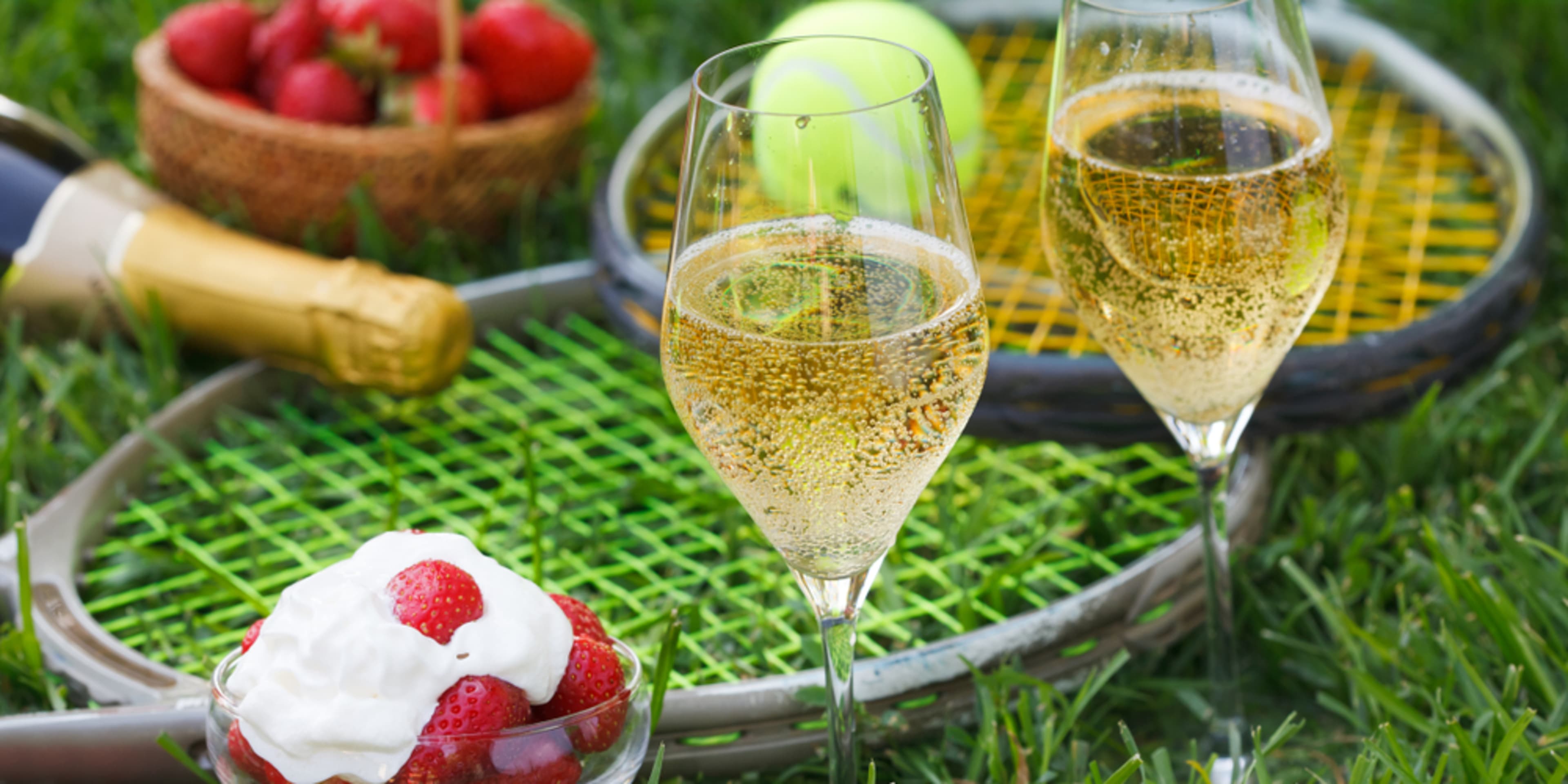 Fraises, champagne et raquettes de tennis sur le gazon