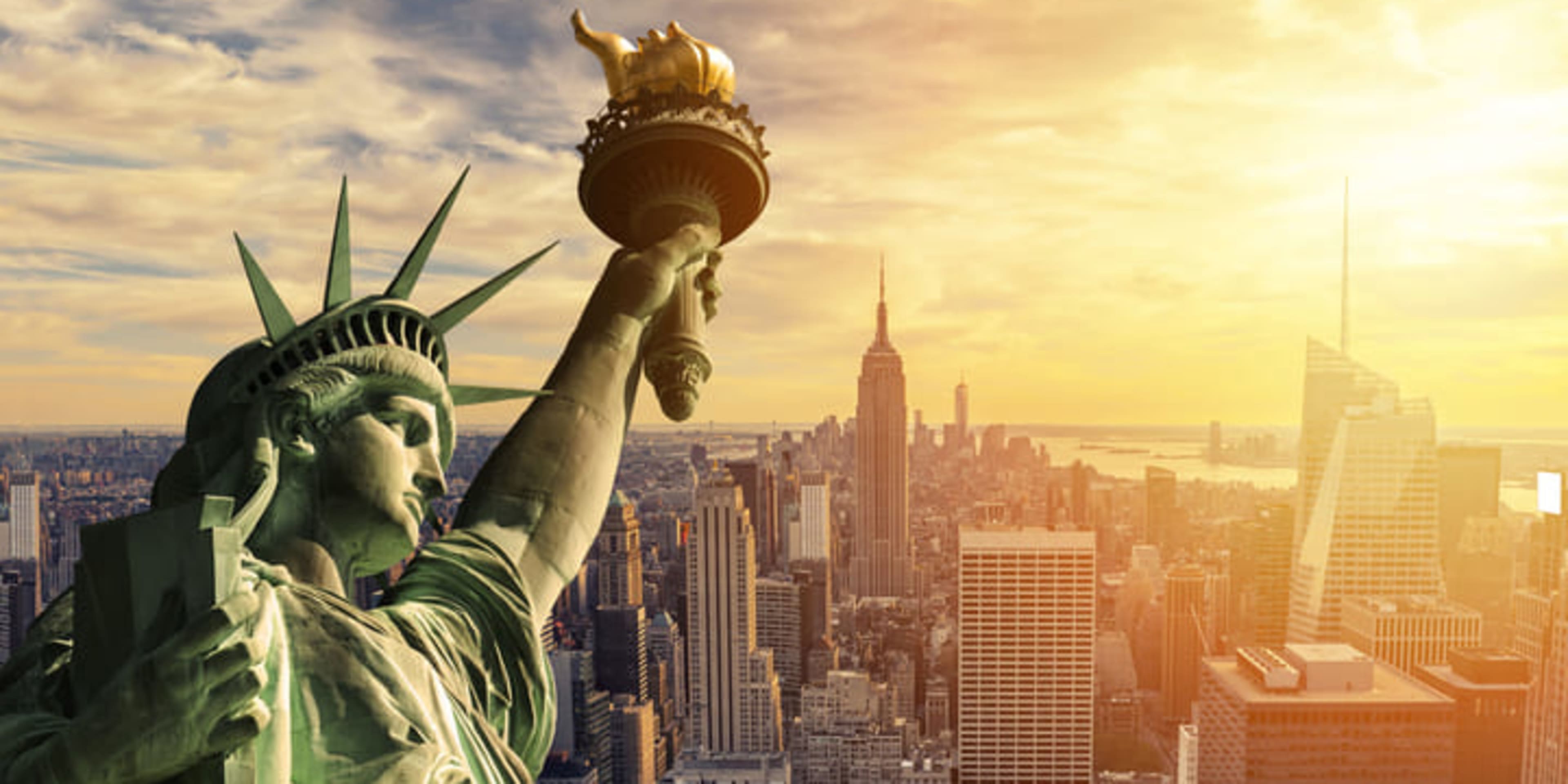 Primer plano de la Estatua de la Libertad con el perfil urbano de Nueva York al fondo.