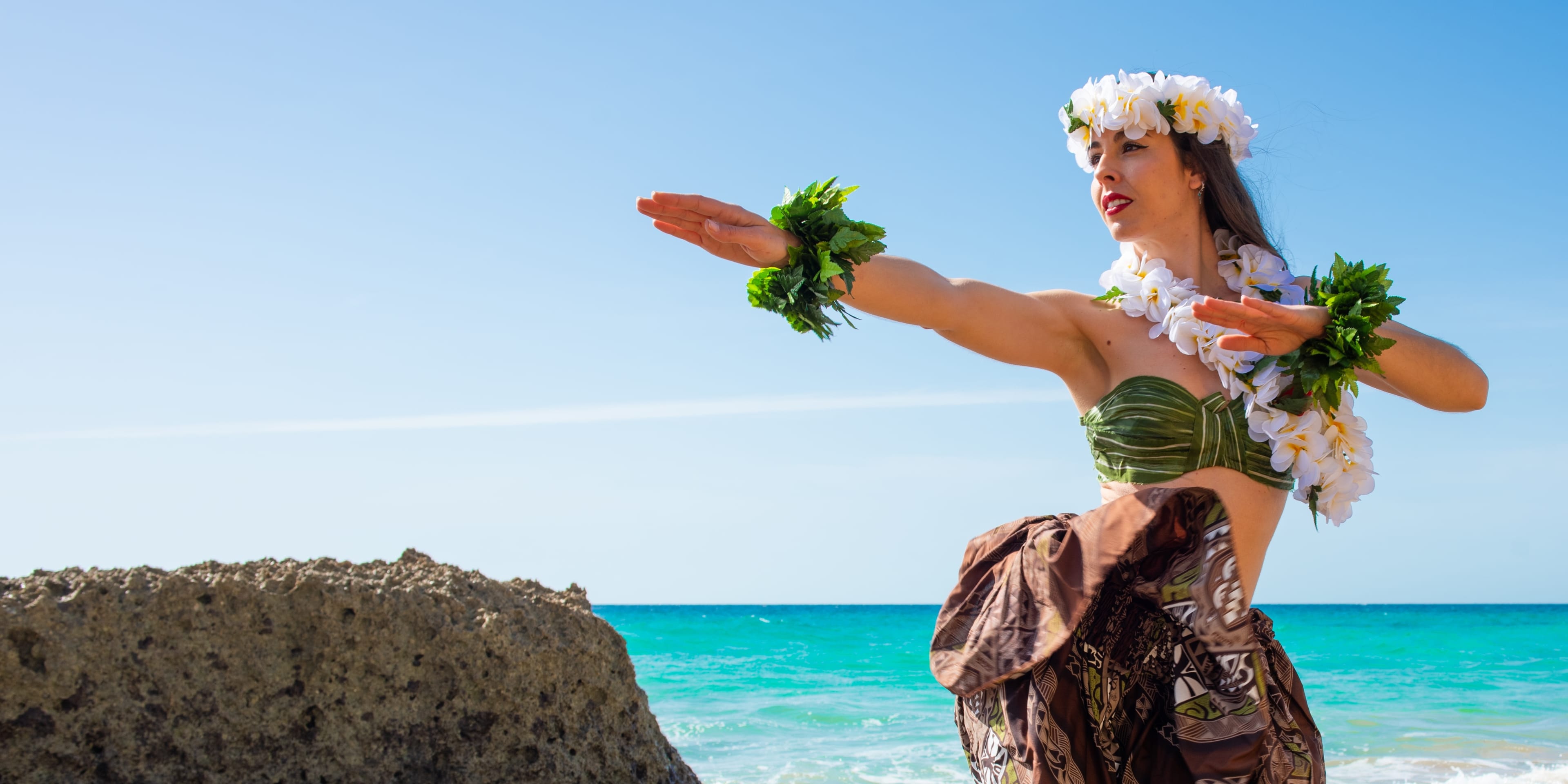 Woman posing at the beach in traditional Polynesian costume.