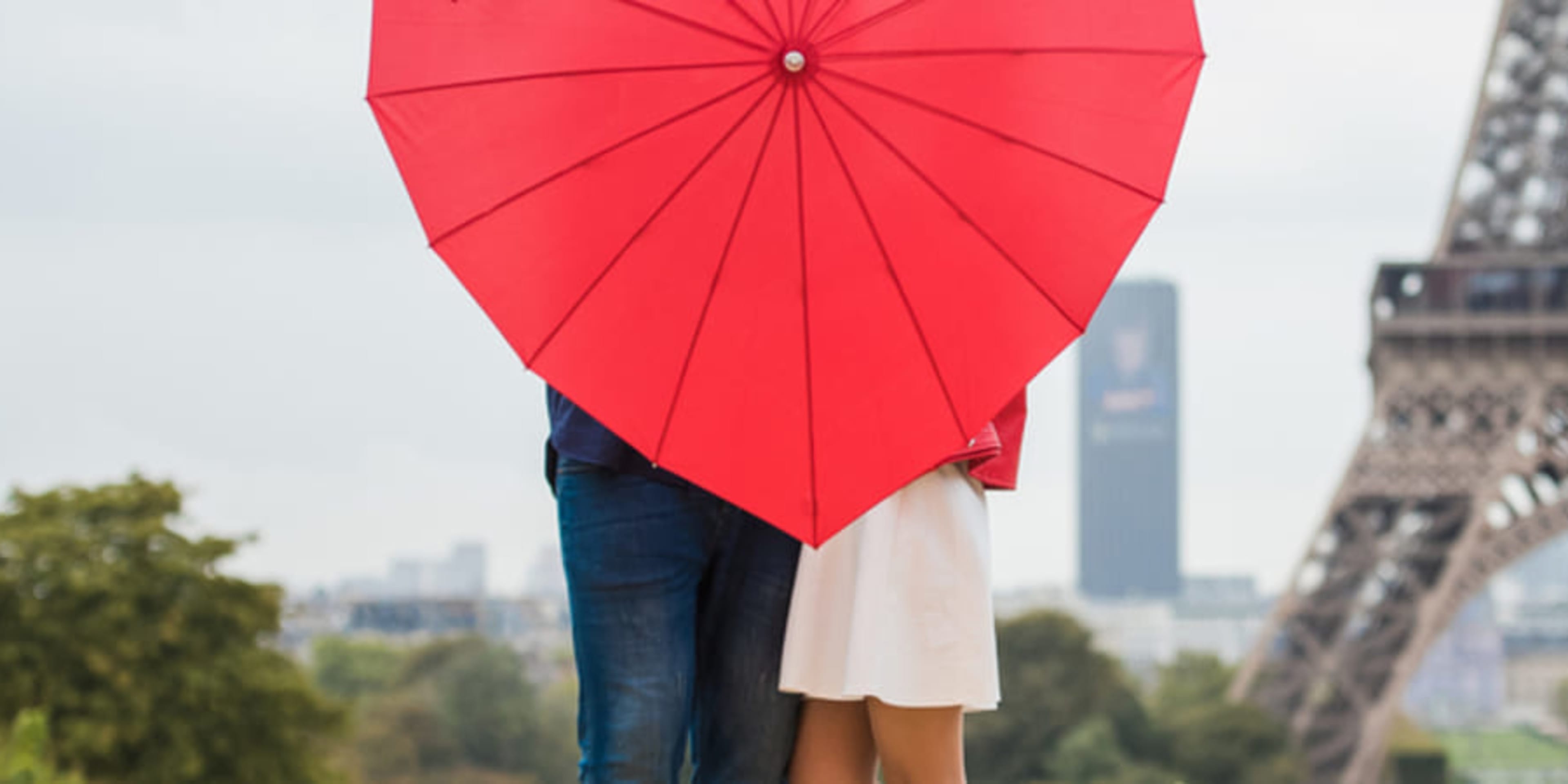 Coppia con un ombrello a forma di cuore davanti alla Torre Eiffel.