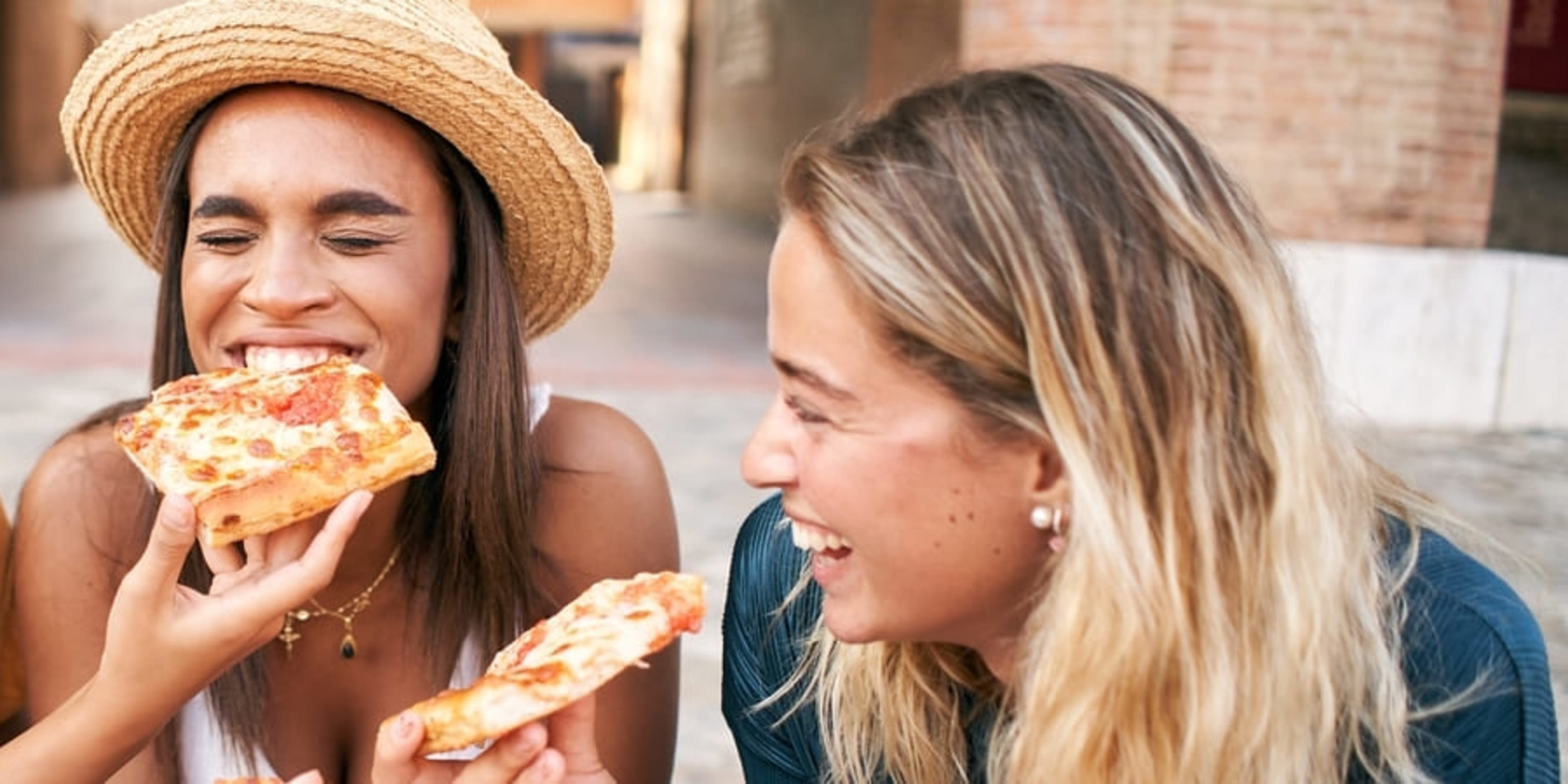 Women laughing and eating pizza in Rome