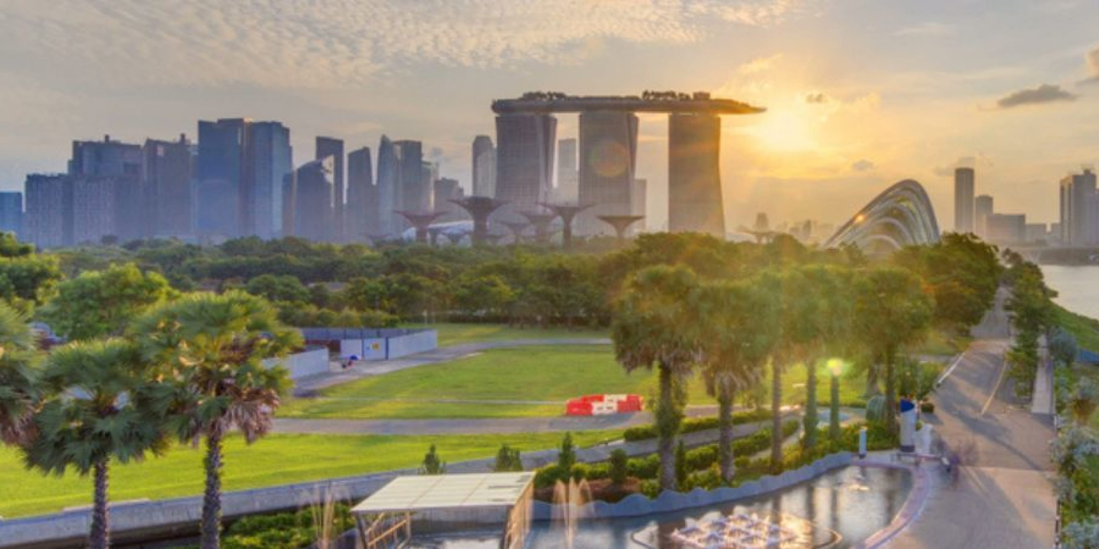 Panorama of the Singapore skyline as sun rises with green space, the river and Marina Bay Sands