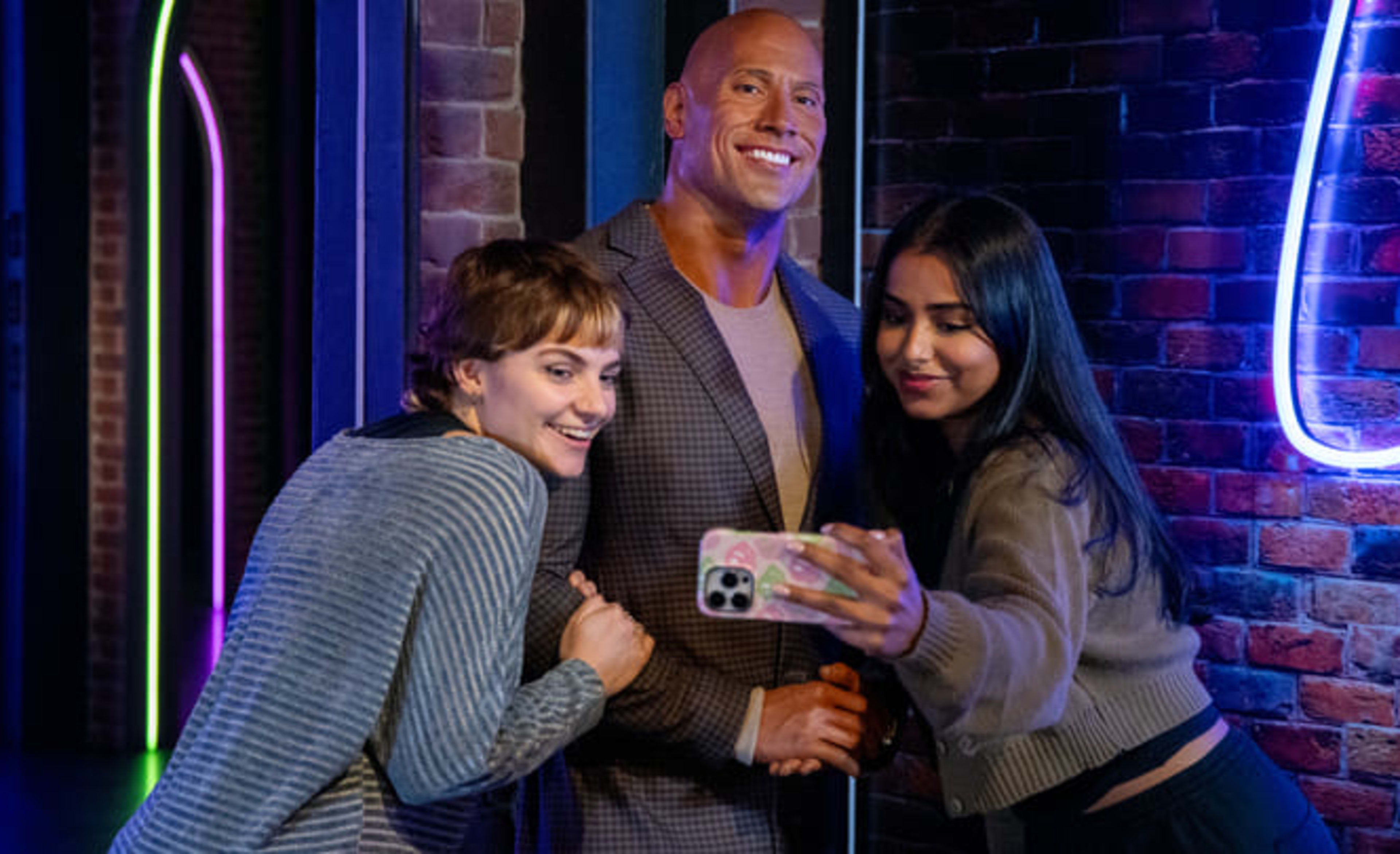 Chicas posando con la estatua de cera de La Roca en el Madame Tussauds, Londres. Guía de visita.