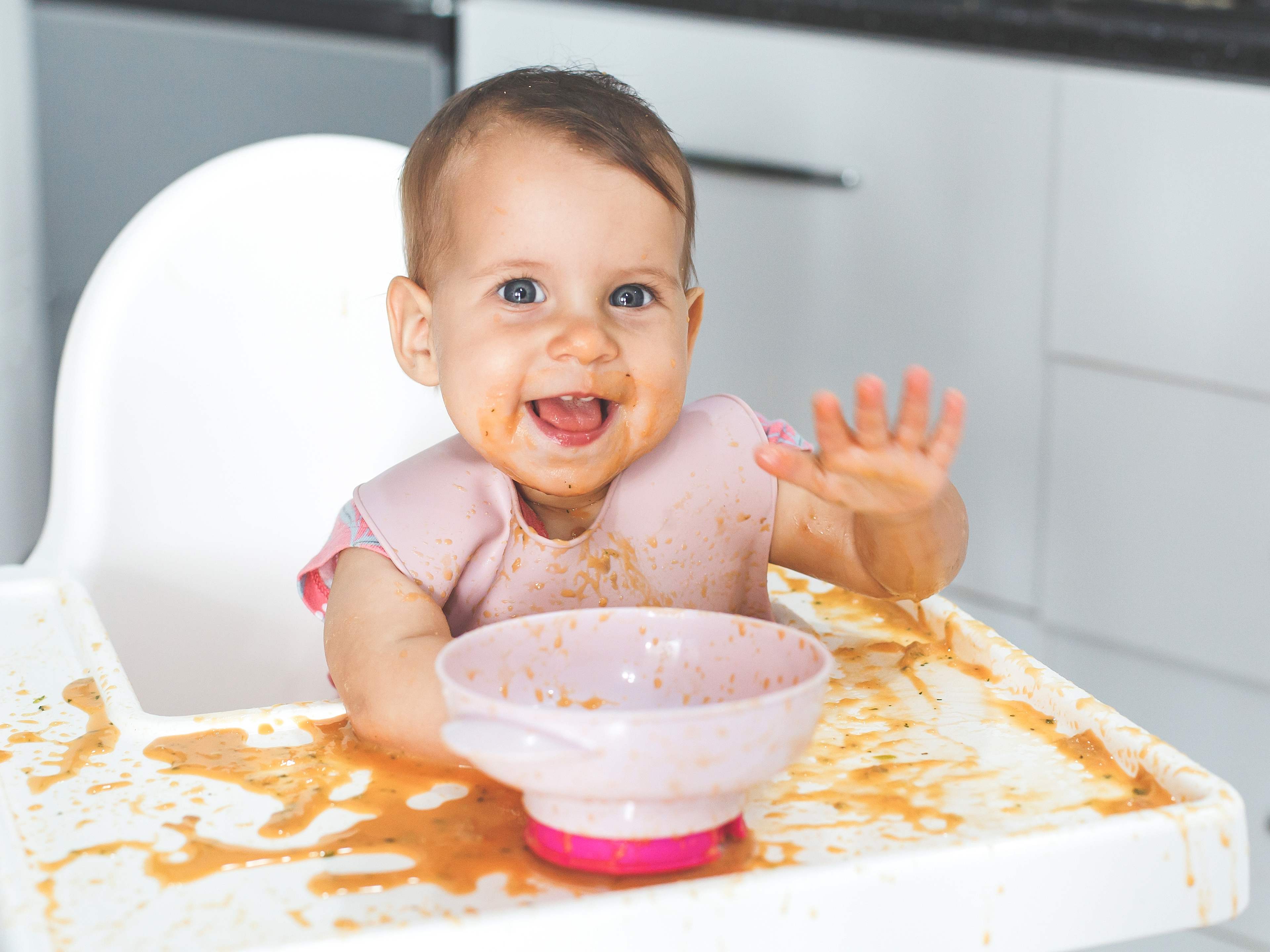 baby eating messily and having fun
