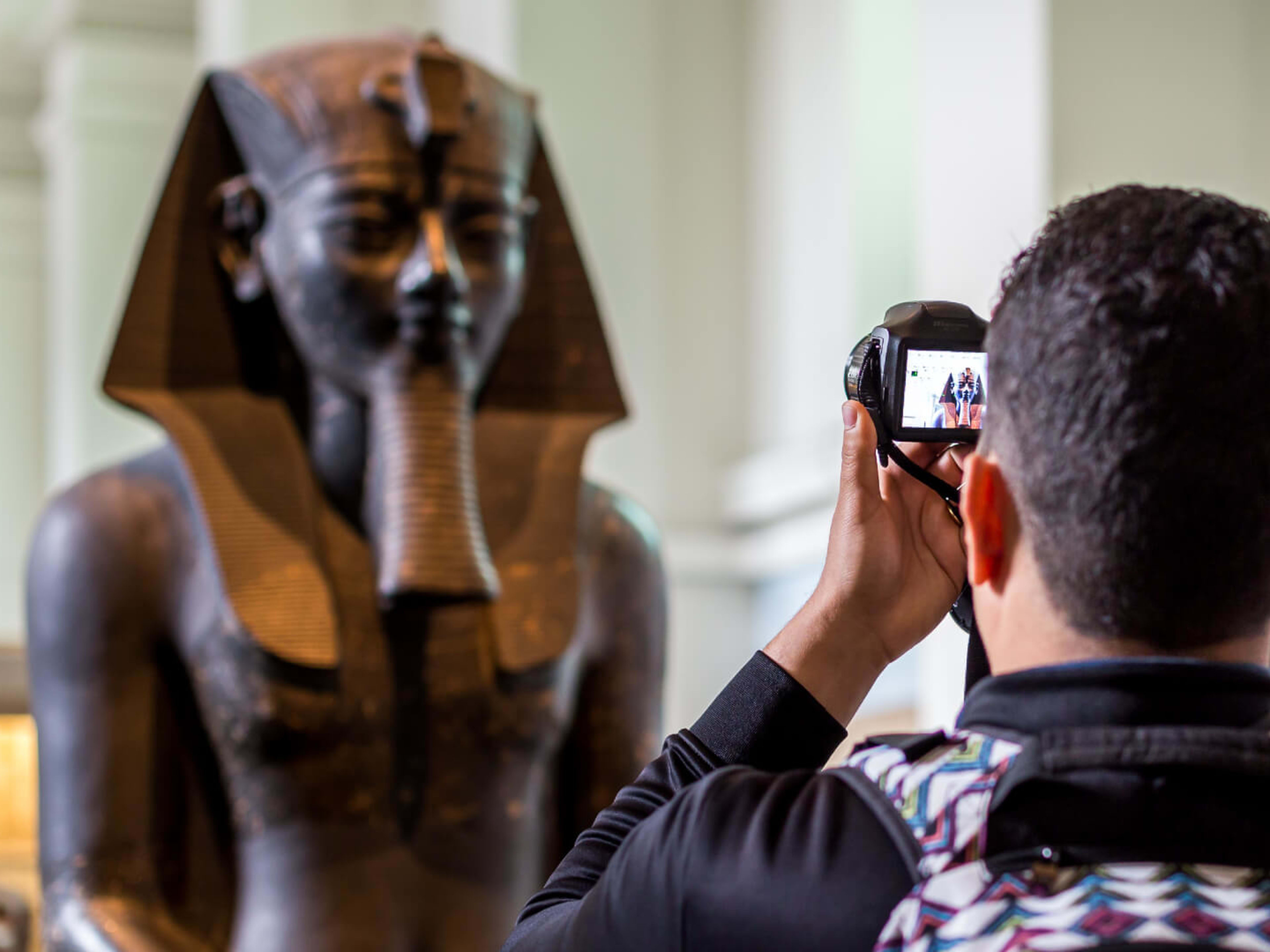 A tourist photographs a statue at the British Museum