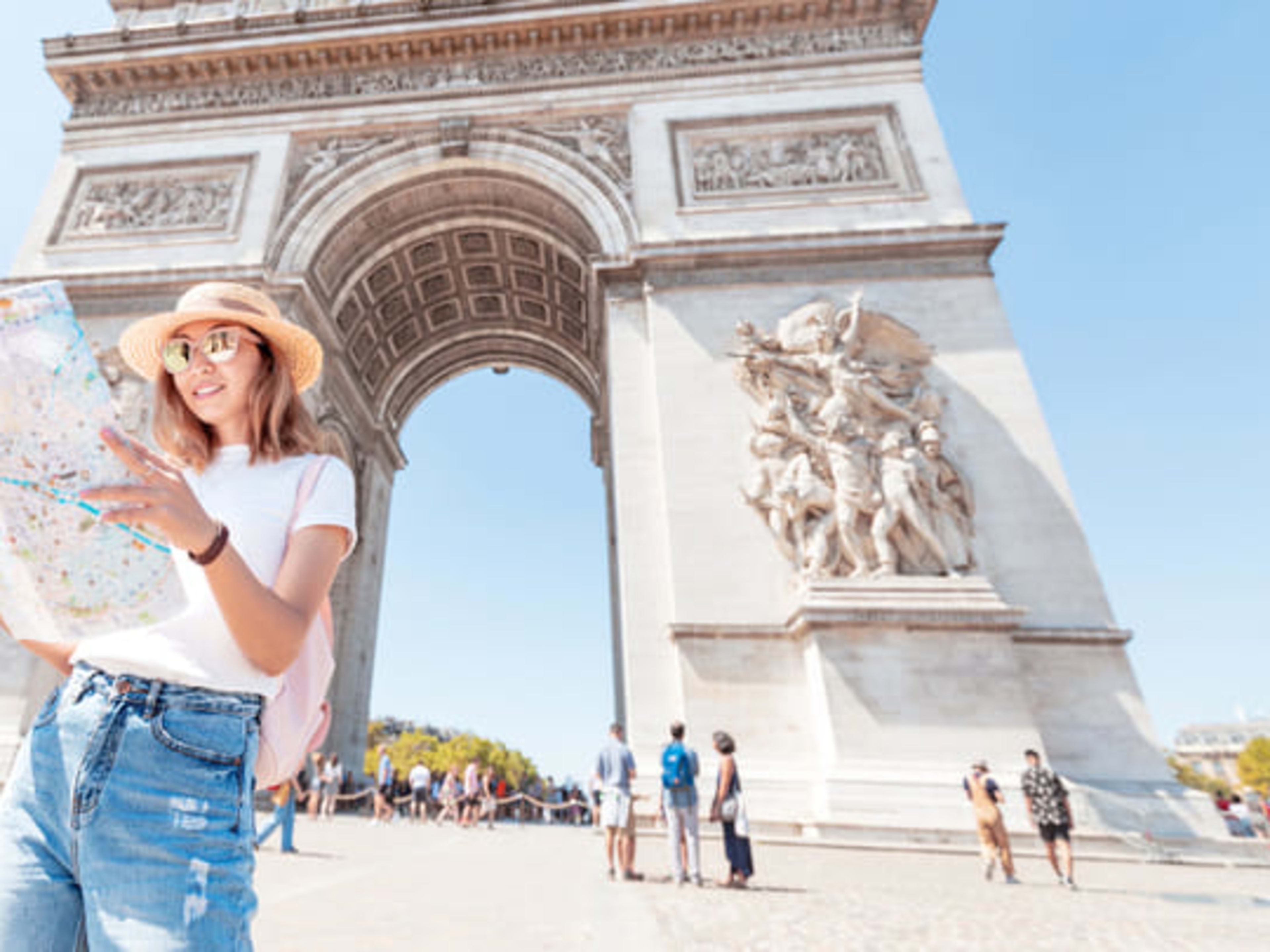 Uma mulher estudando um mapa perto do Arco do Triunfo em Paris
