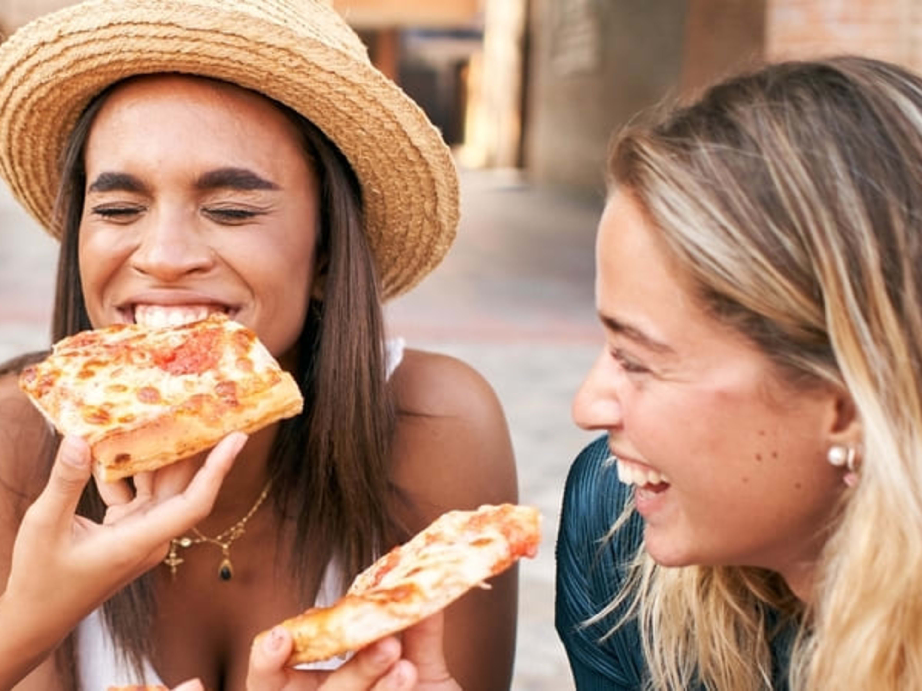 Women laughing and eating pizza in Rome