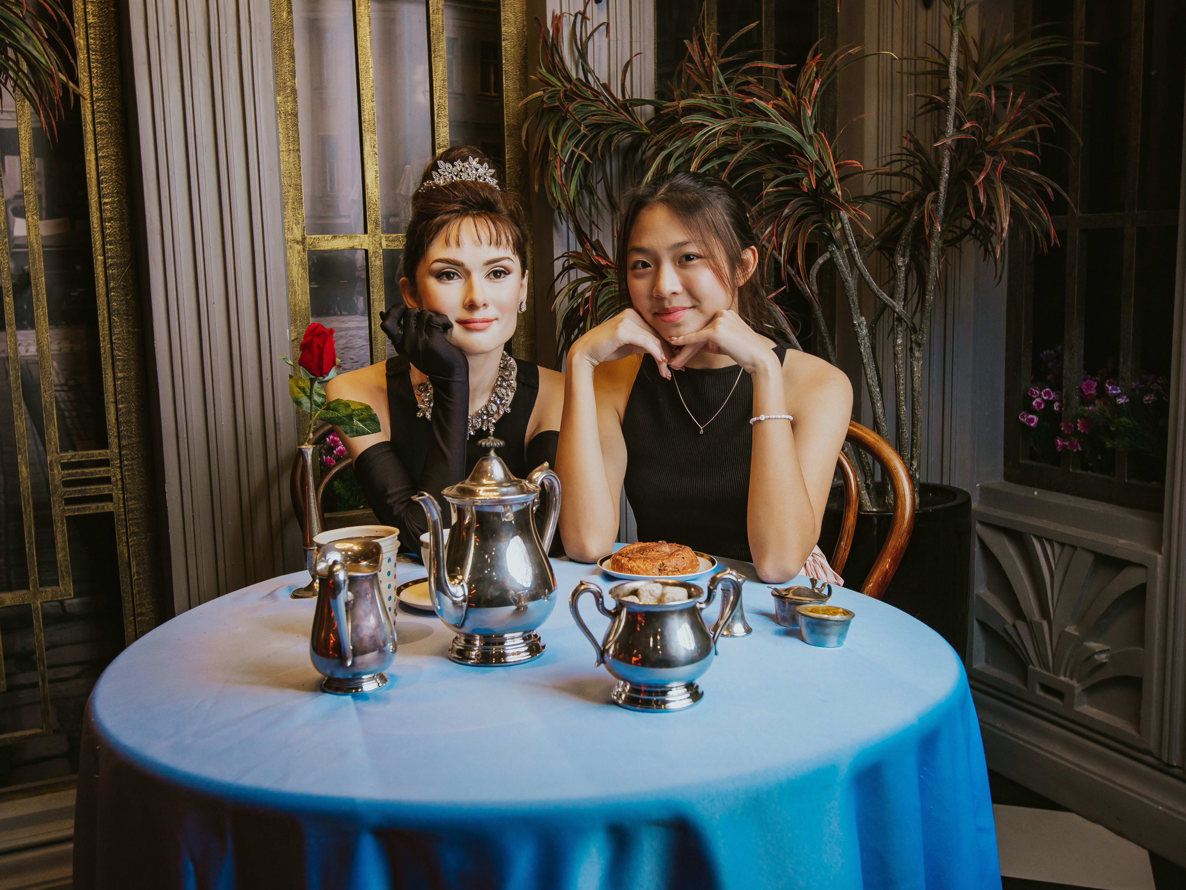 woman sitting next to a wax figure of audrey hepburn in madame tussauds vegas
