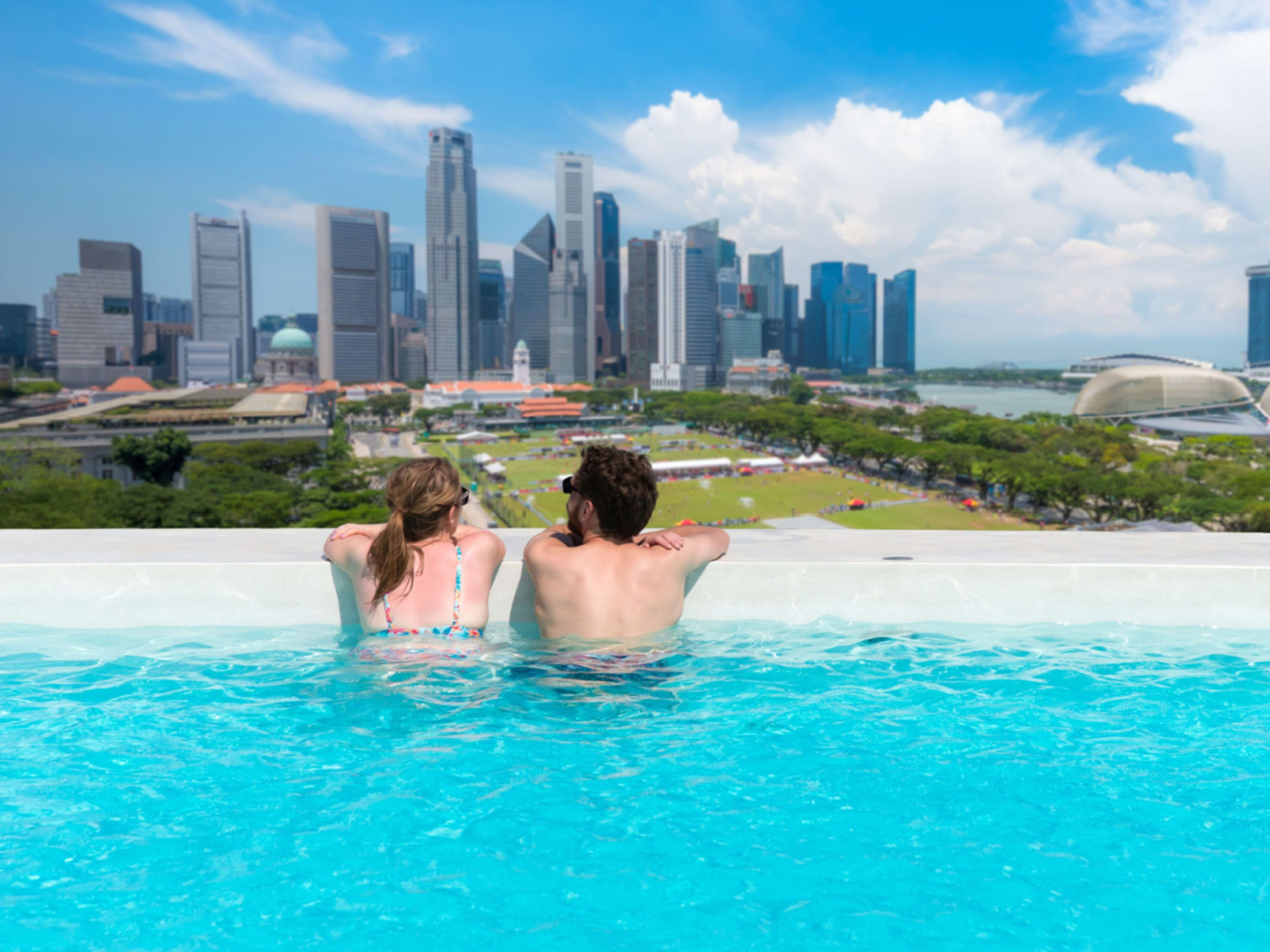 Couple look from a rooftop pool over Singapore Marina