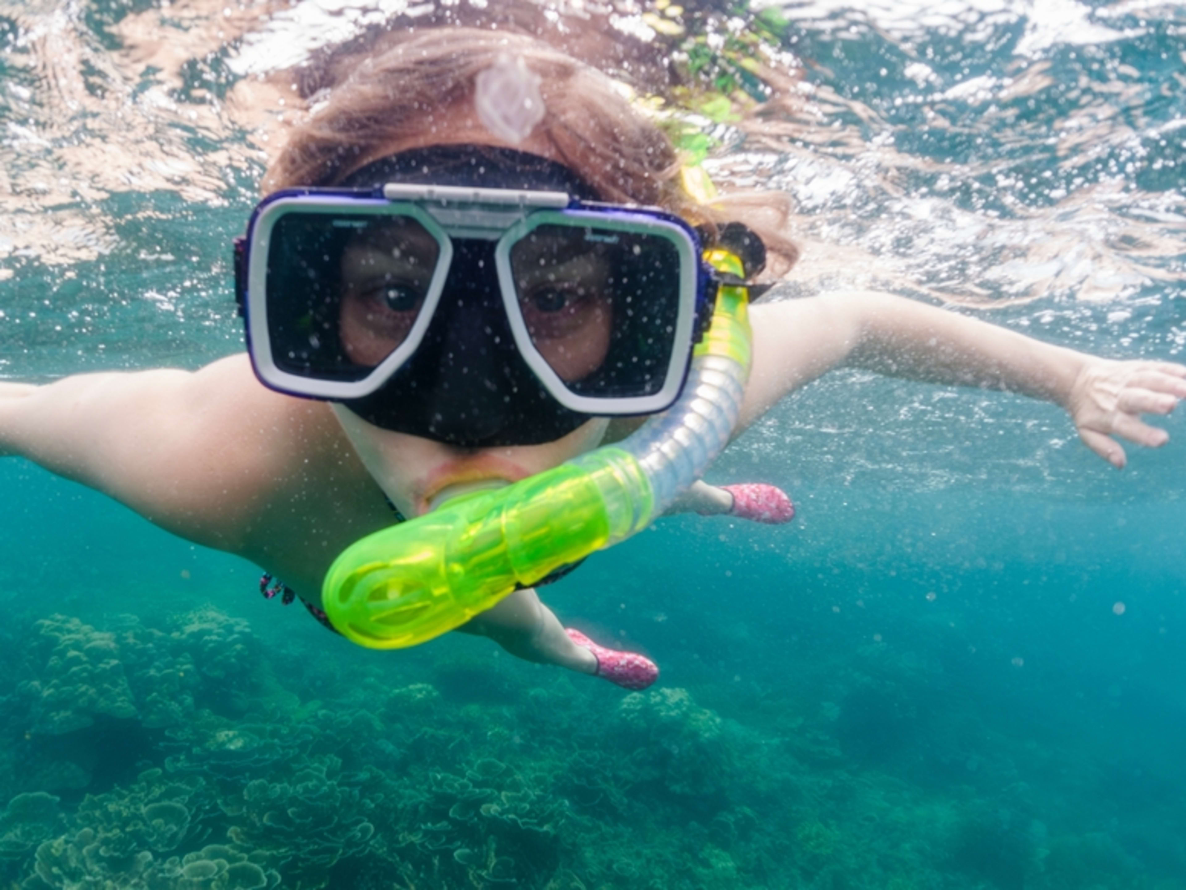 Primer plano de un niño buceando con esnórquel en el mar. Dónde viajar en abril para disfrutar del calor.