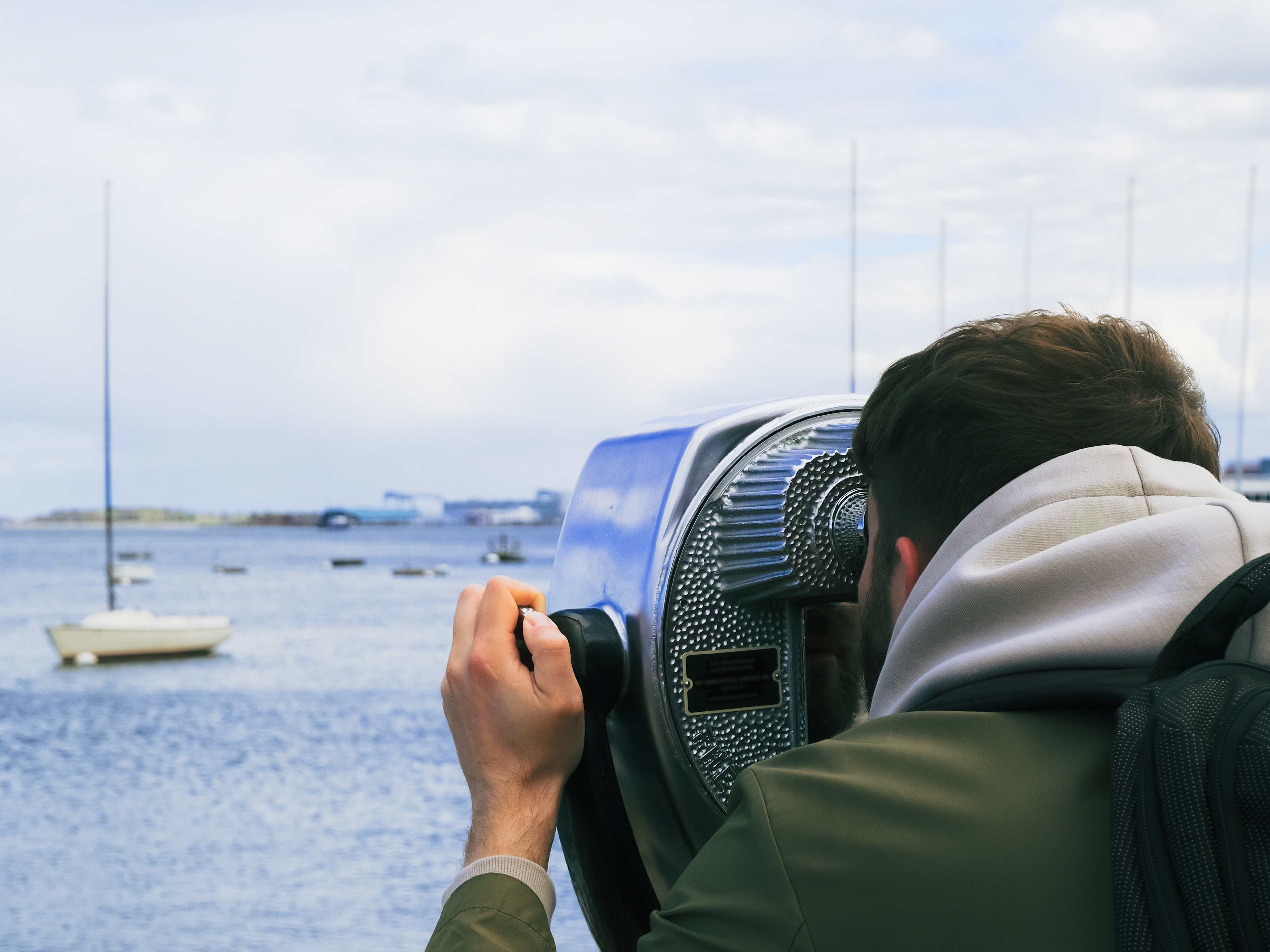 Man Looking Through Binoculars at Boston Waterfront
