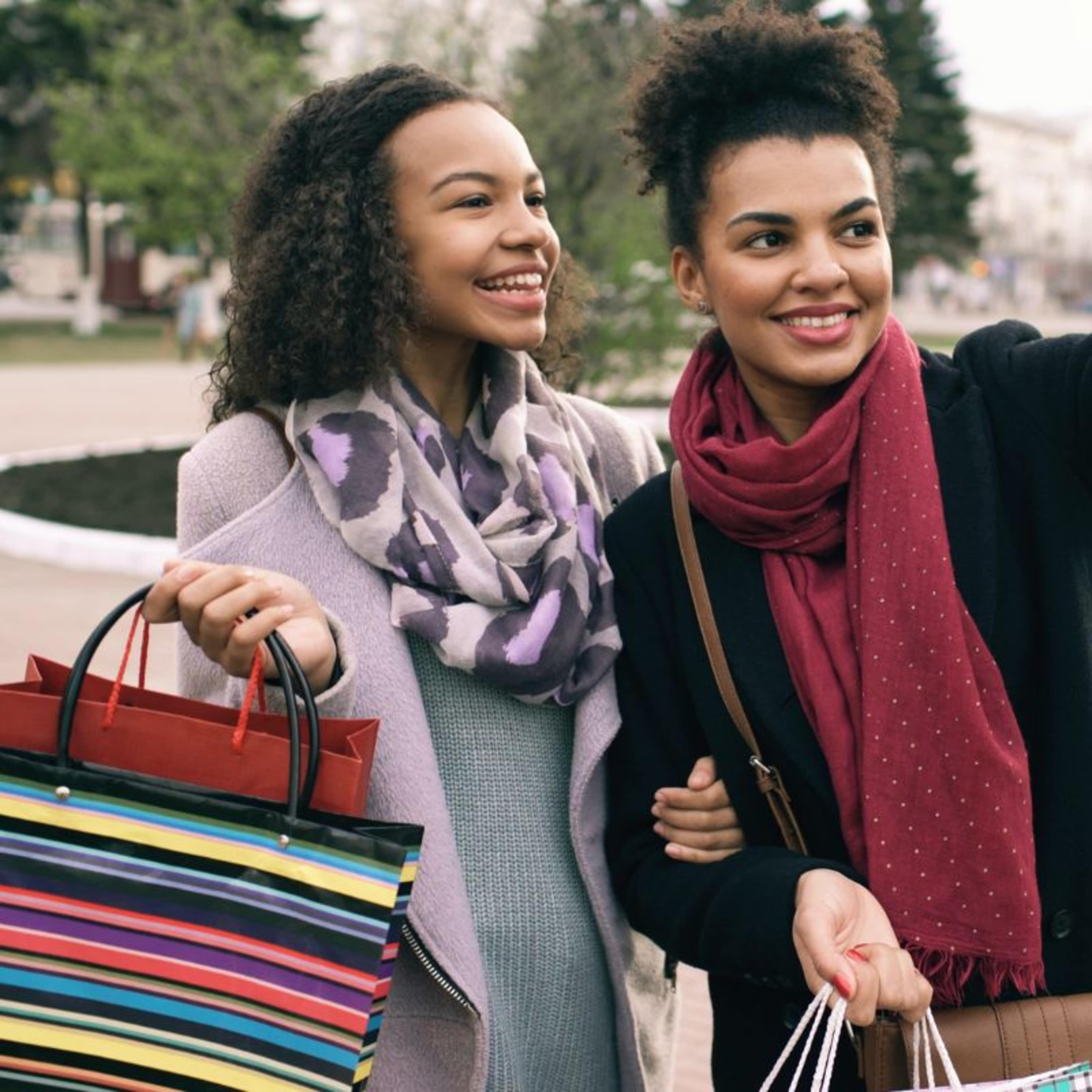 Two women smiling for a selfie, whilst holding shopping bags