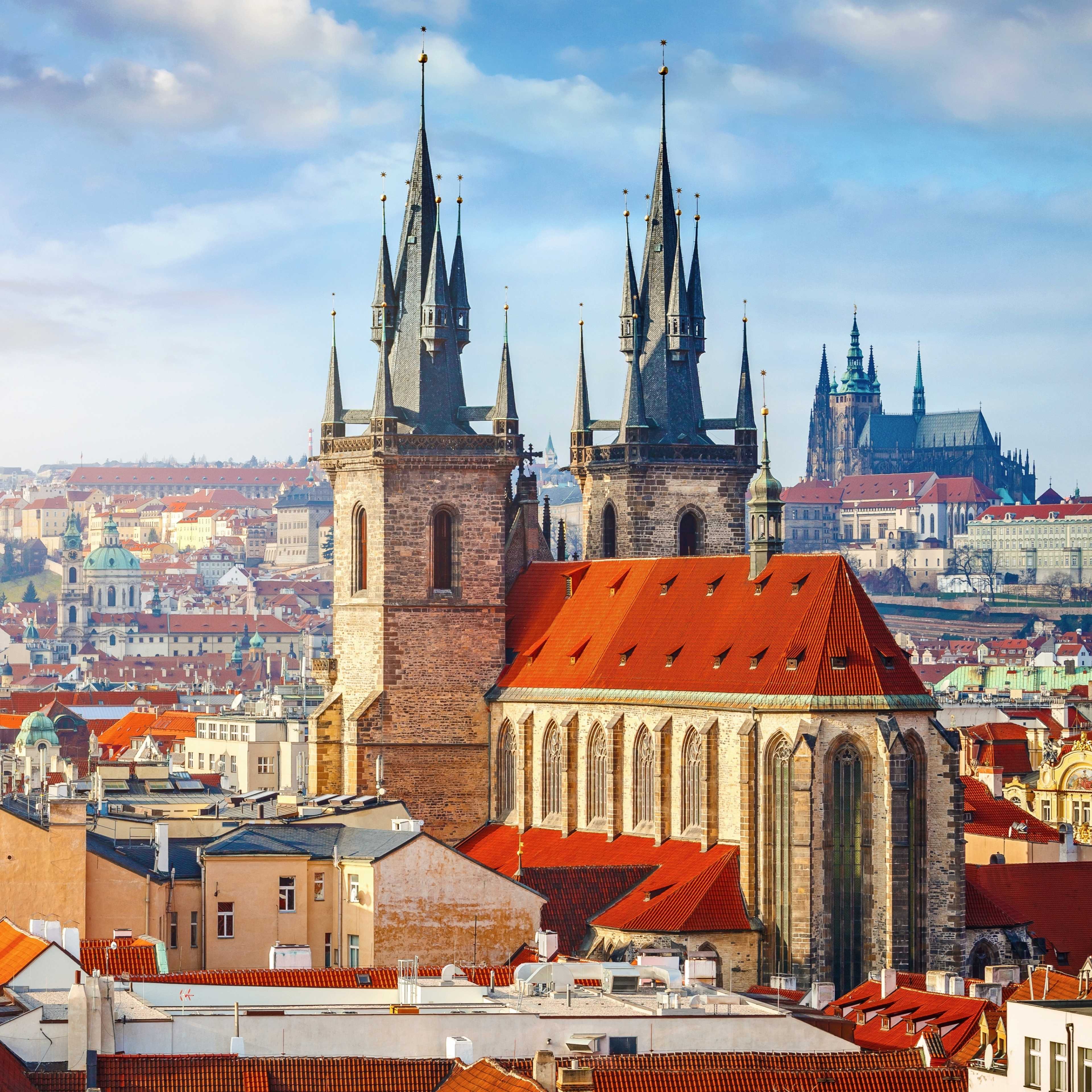 Blick auf die historischen Gebäude von Prag an einem sonnigen Tag mit der Prager Burg im Hintergrund.