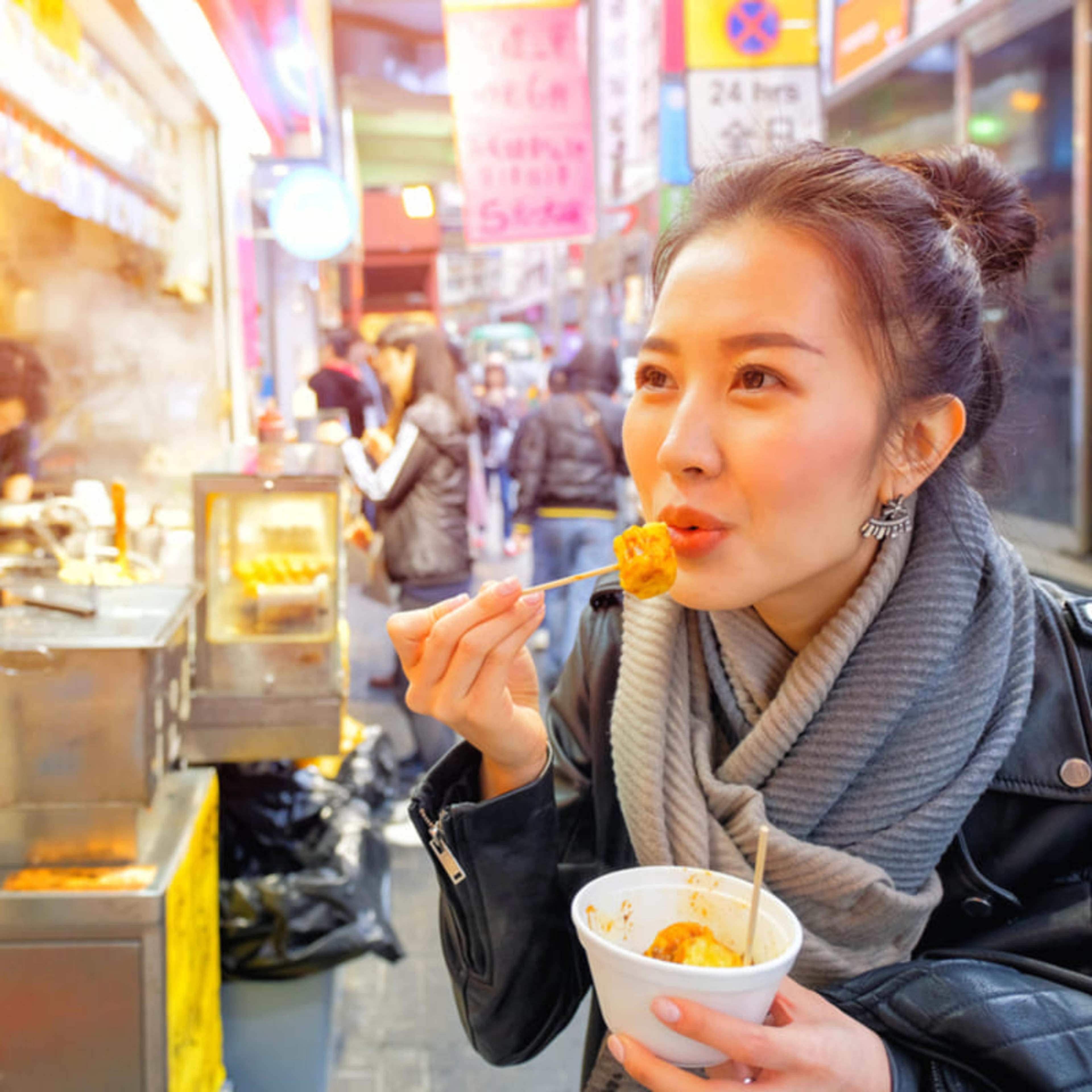 ホーカーセンターで出来立てのテイクアウト用小籠包を食べる女性。