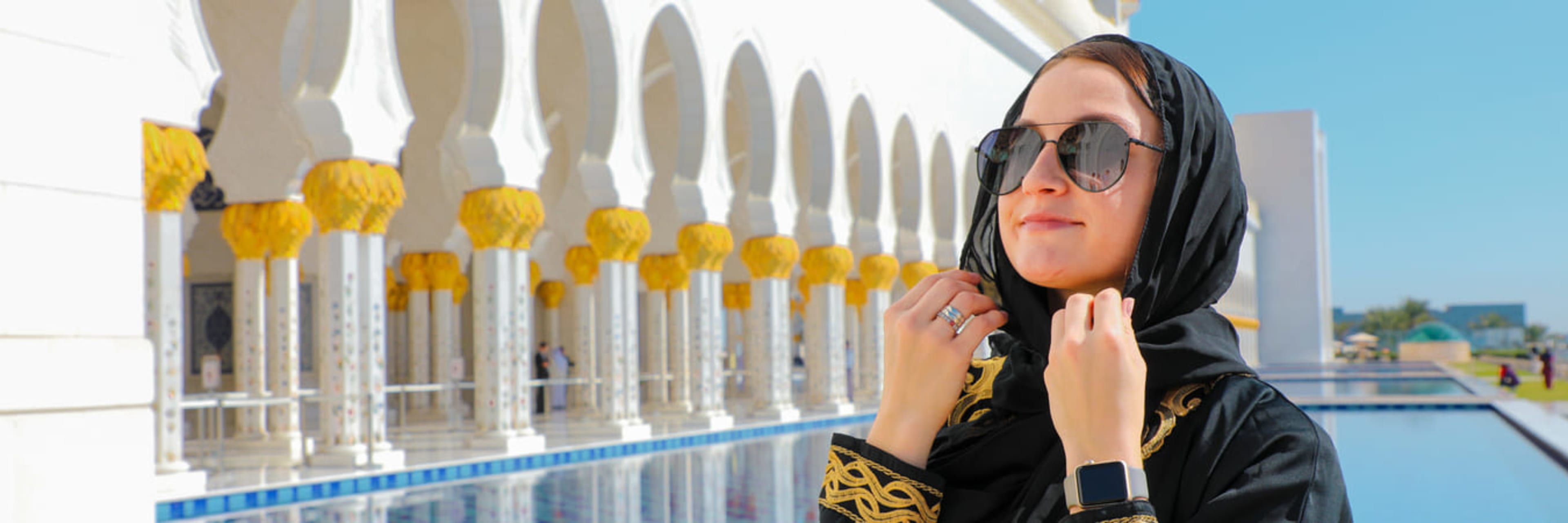 Woman exploring the archways and reflective pools in the grounds of Sheikh Zayed Grand Mosque in Abu Dhabi.