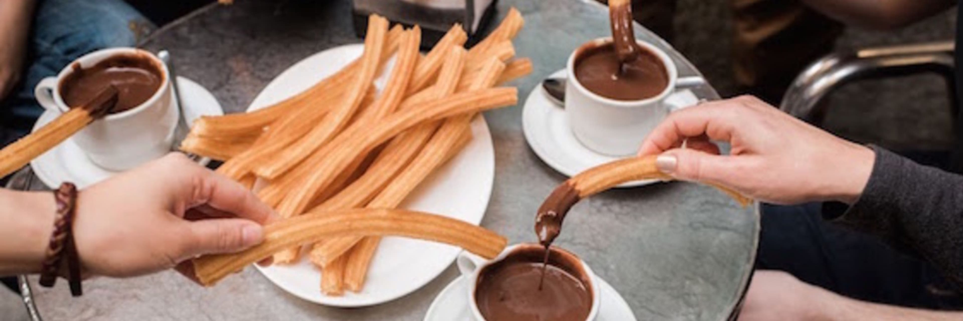 Friends sharing churros with dipping chocolate.
