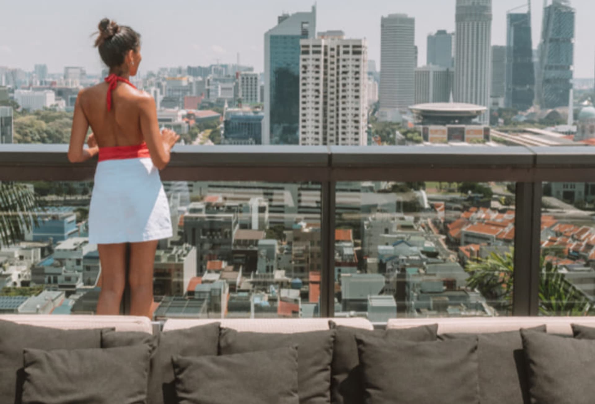 Woman gazing at the Singapore skyline from a hotel balcony