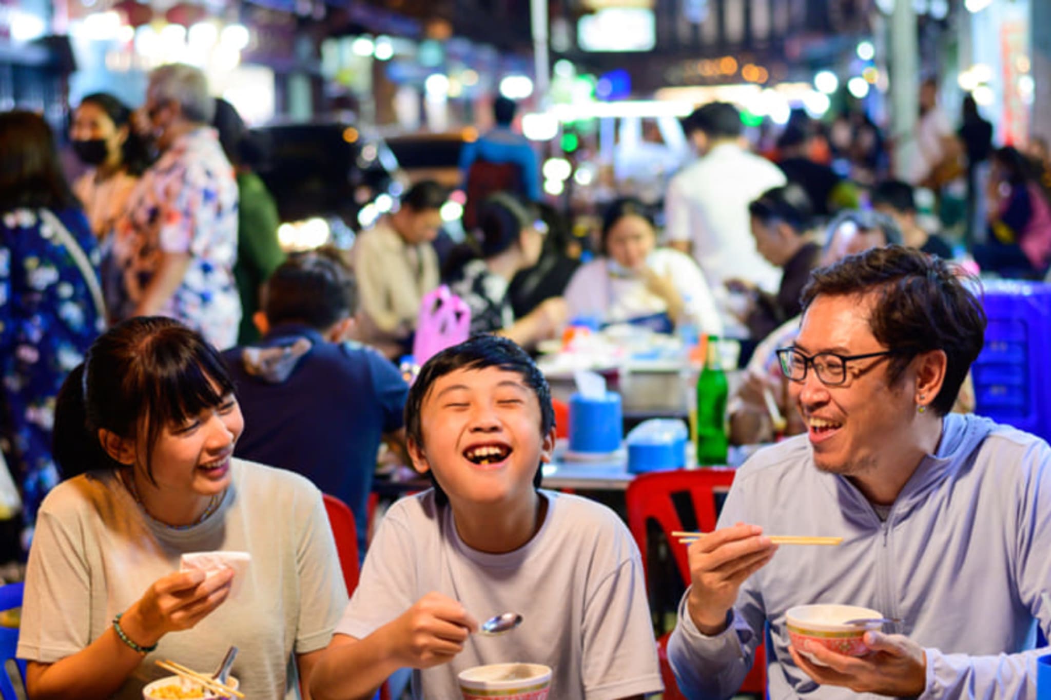Family eating street food together in Bangkok's Chinatown.
