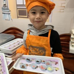 Young boy holding a tray of chocolate ingredients in an Art of Chocolate workshop.