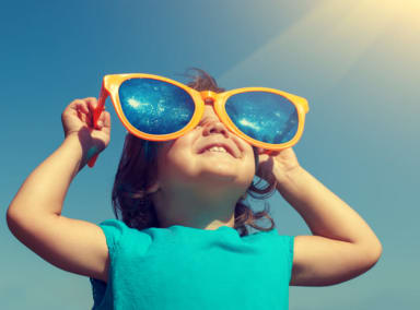 Child in enormous sunglasses on a bright, sunny day.