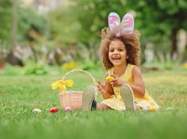 Little girl wearing bunny ears on a traditional Easter egg hunt.