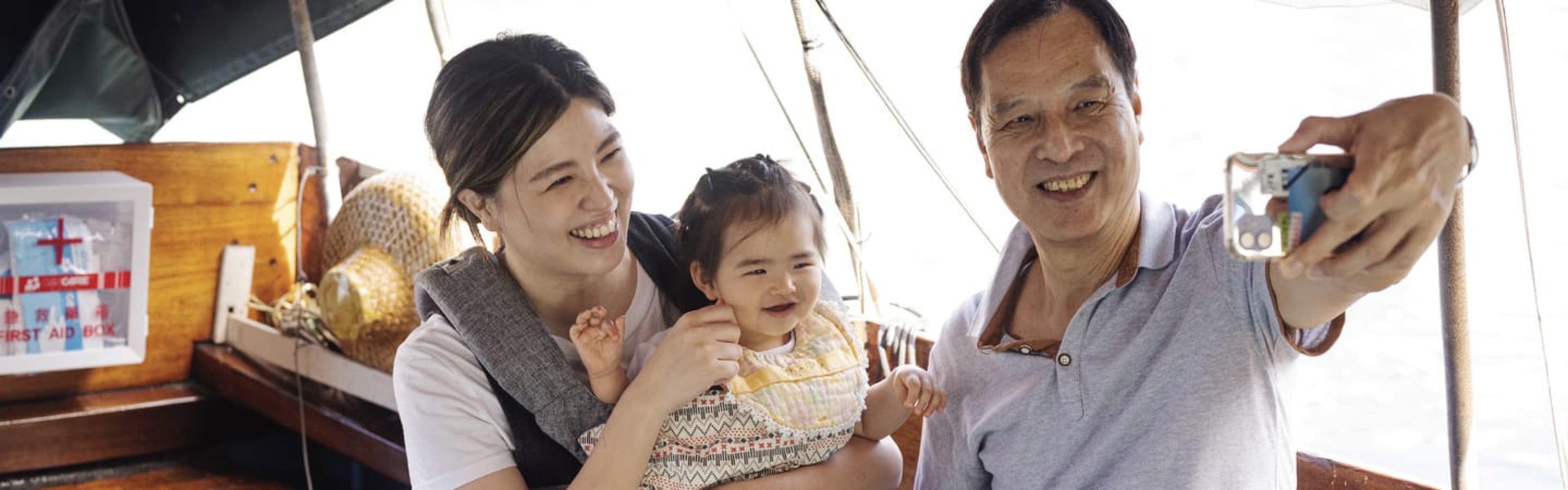 Family taking a selfie on board a sampan boat tour.