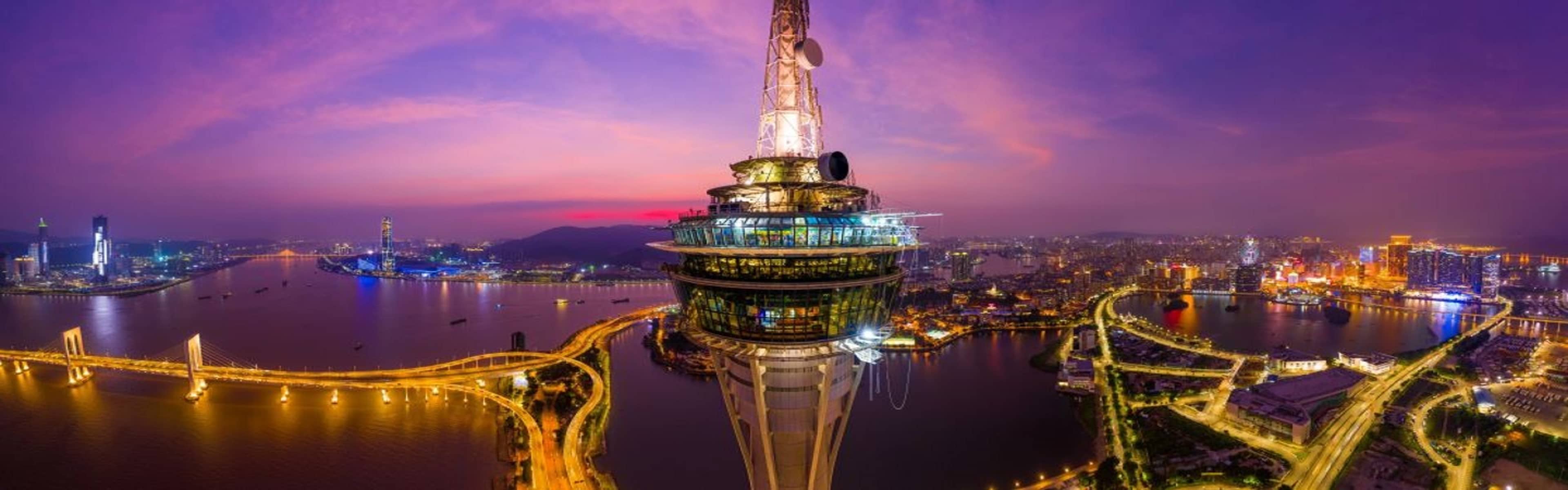 Macau Tower observation deck and the city skyline by night.