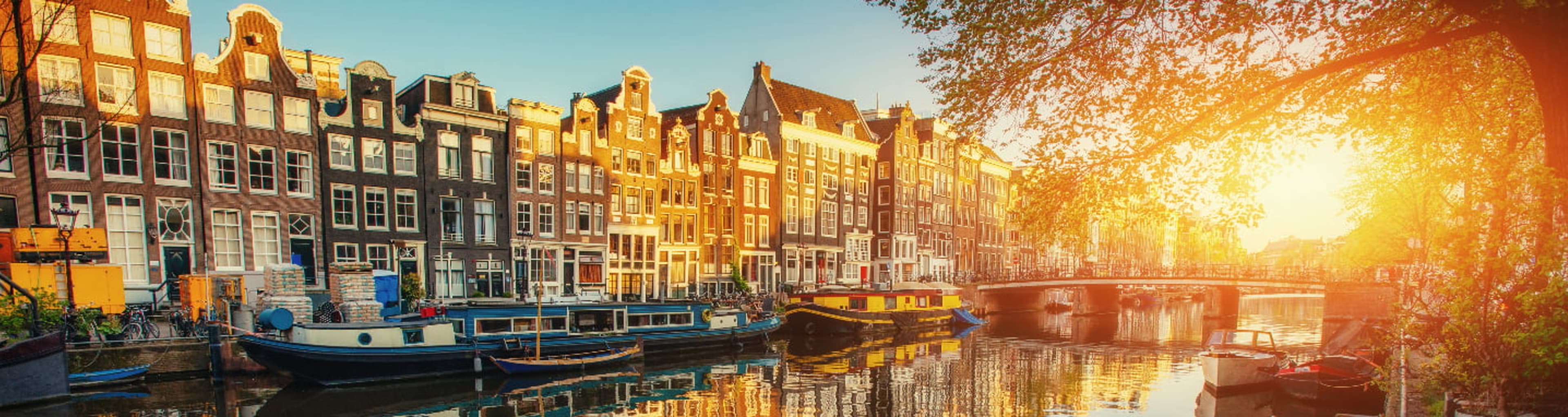 Several boats moored beside Amsterdam's iconic canal houses