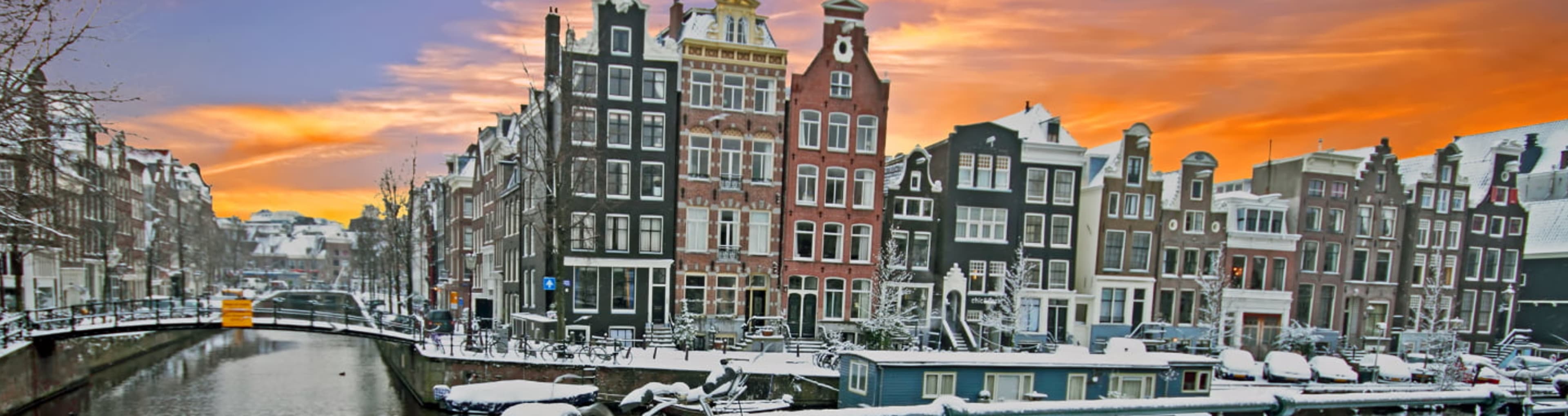 Snowed-over bicycle leaning against the railings of an Amsterdam canal