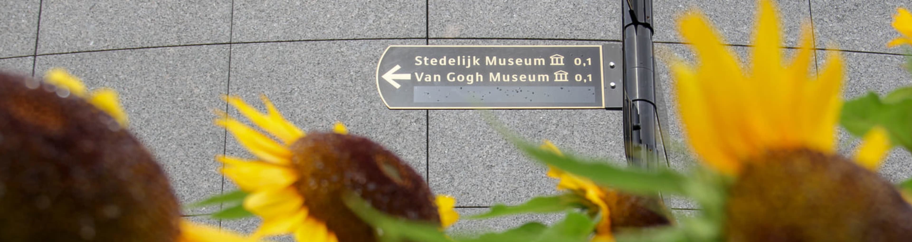 Cartel al Van Gogh Museum con girasoles en primer plano, Ámsterdam.