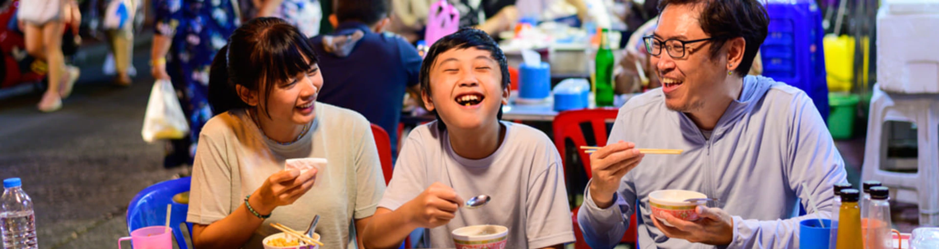 Family eating street food together in Bangkok's Chinatown.