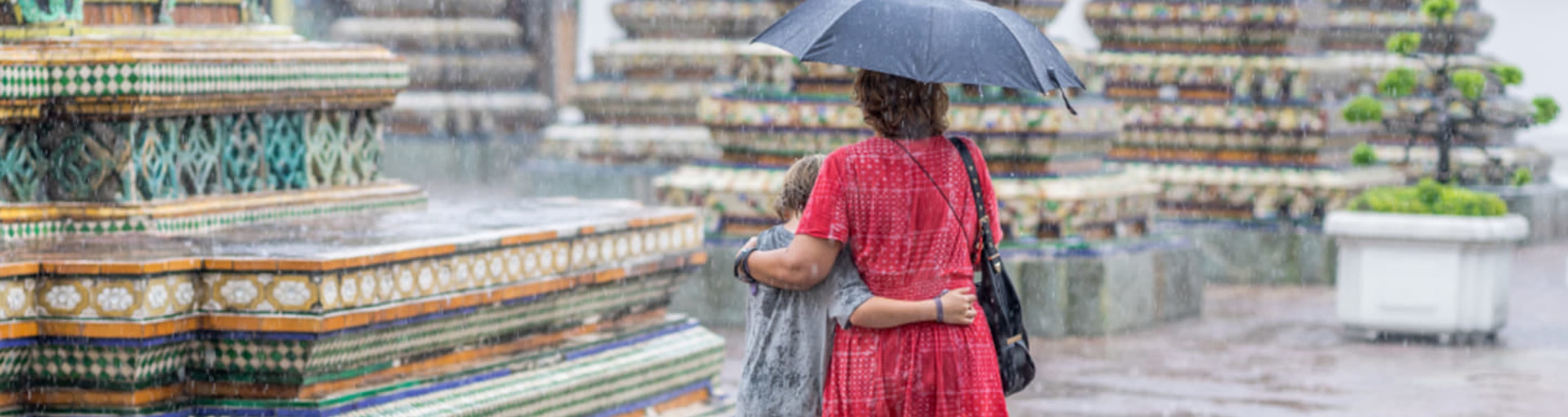 Woman and child walking in the rain under an umbrella in Bangkok.