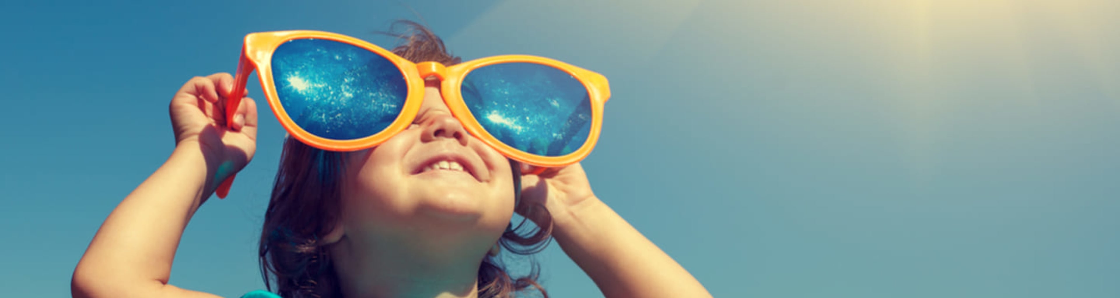 Child in enormous sunglasses on a bright, sunny day.