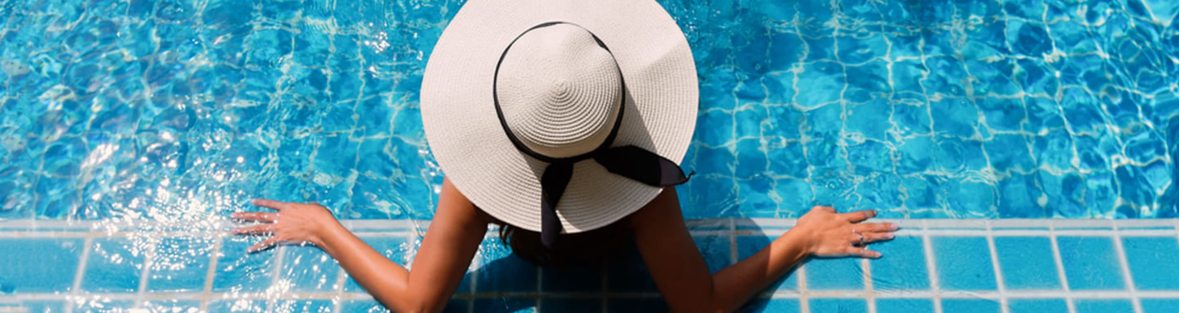 Aerial view of woman wearing a large sun hat in a swimming pool.